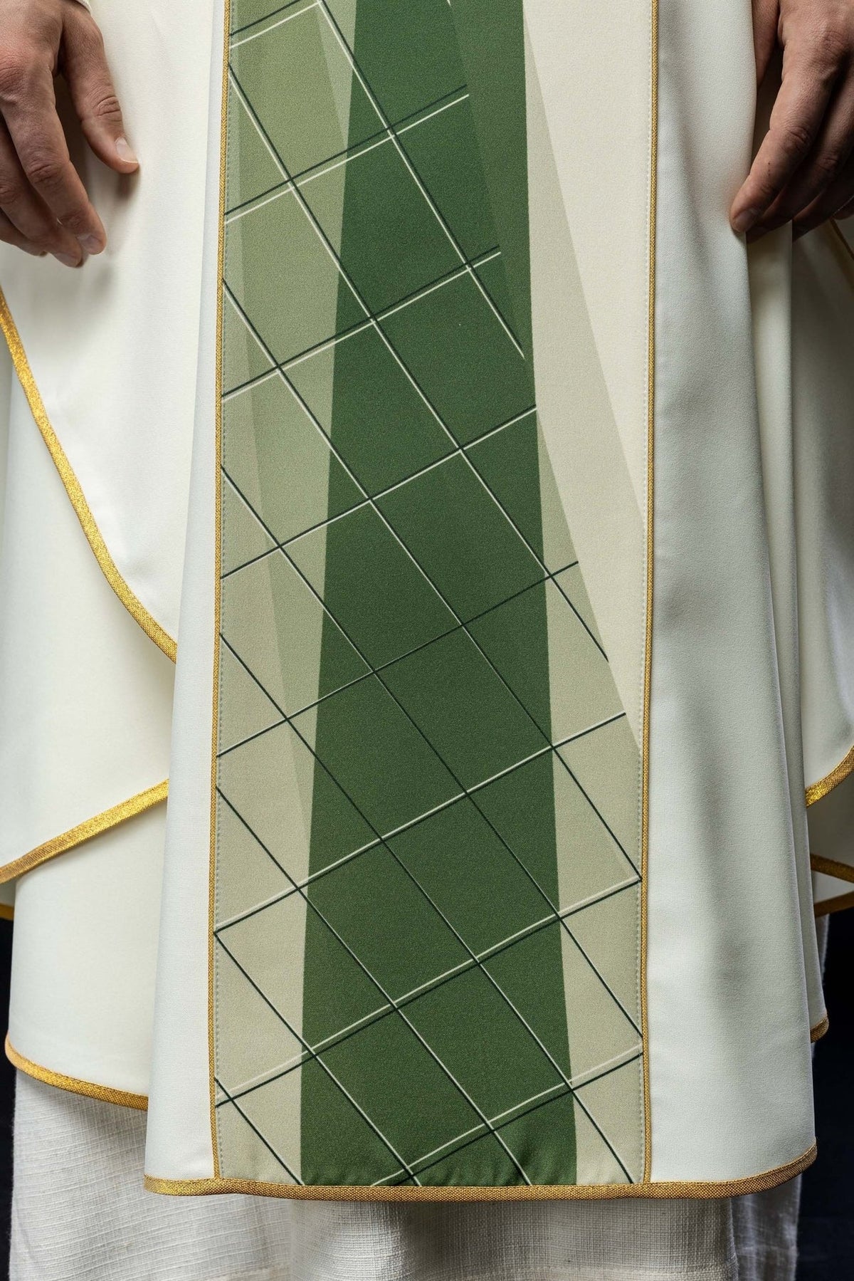 White chasuble close-up showing fish, green cross and gold trim