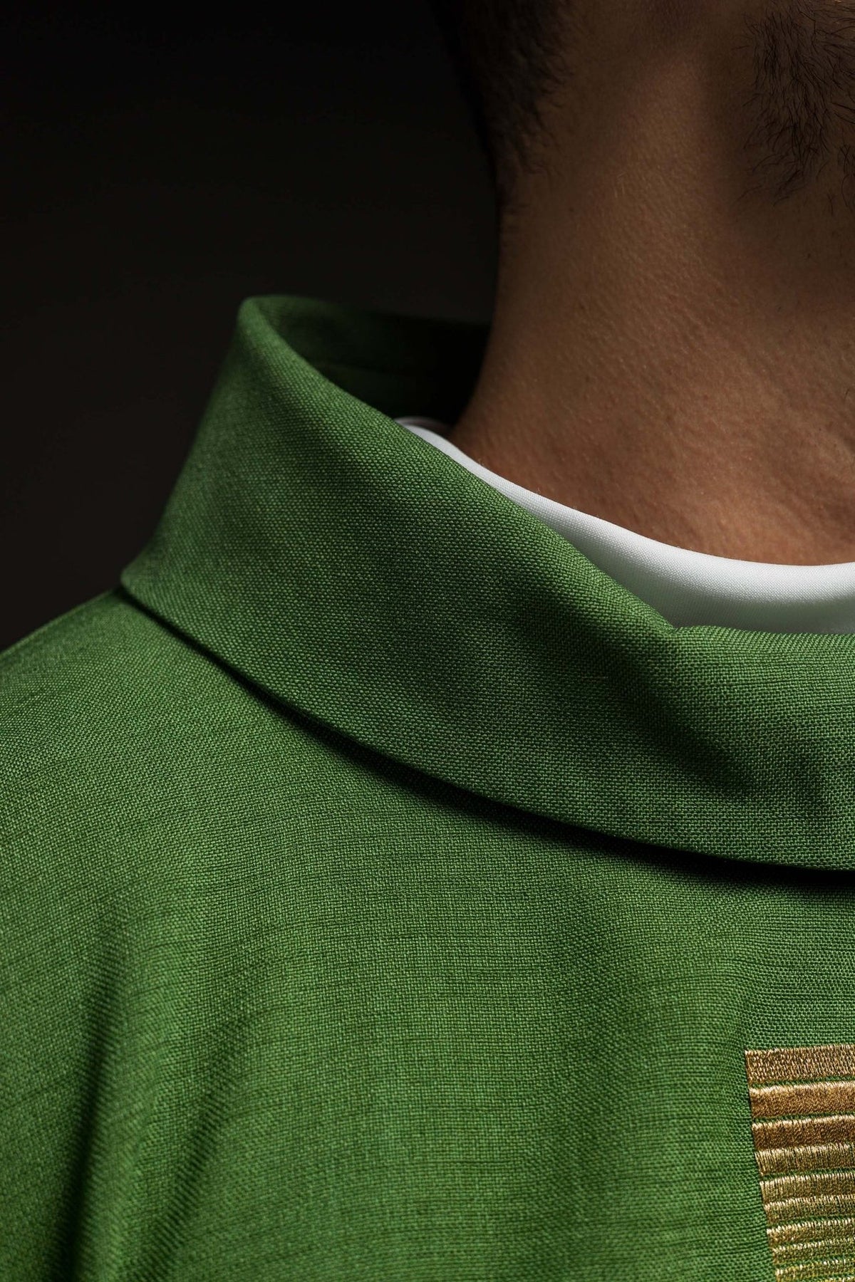 Green chasuble close-up showing the stand-up collar and woven green fabric