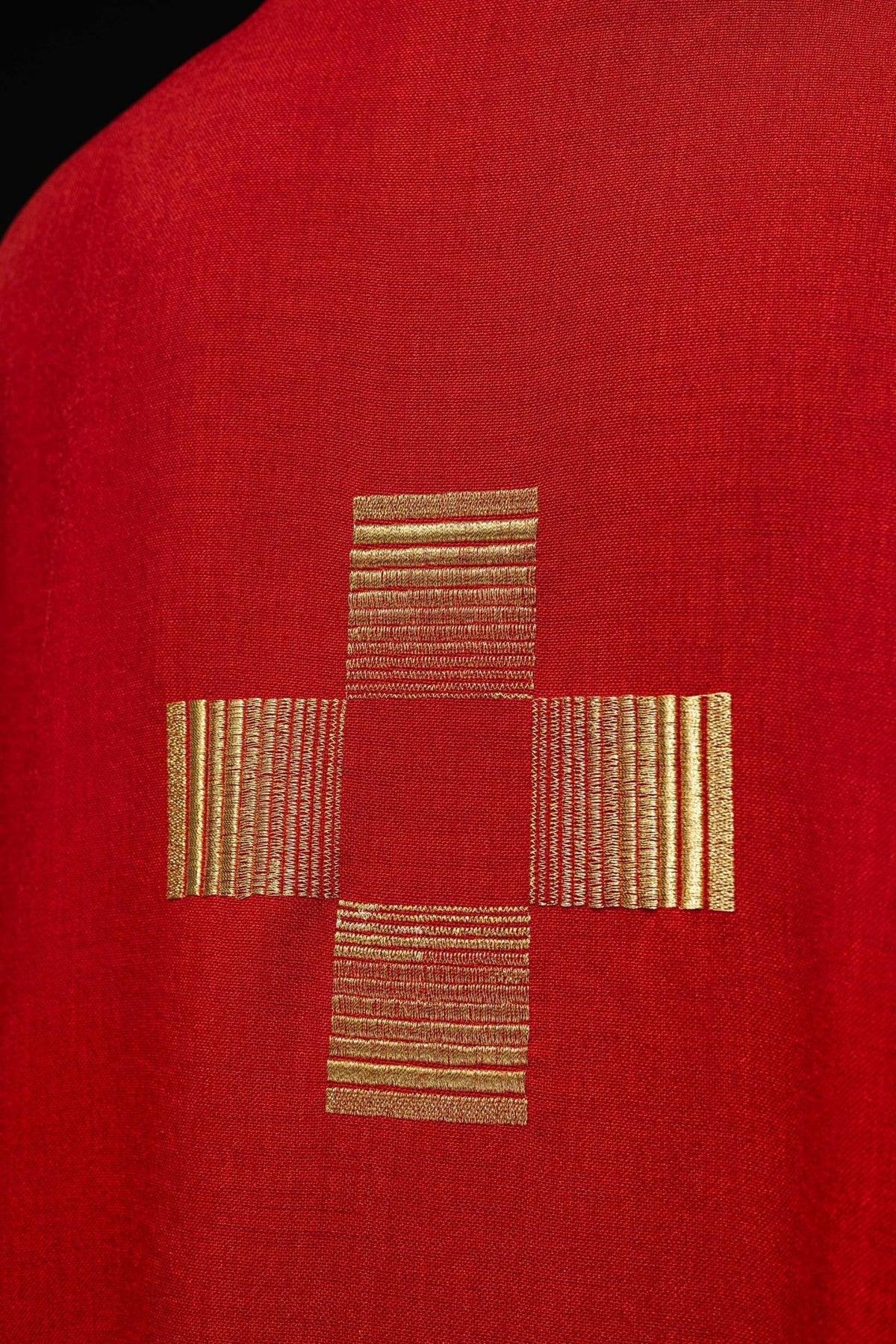 Red chasuble close-up showing gold cross embroidery on red fabric