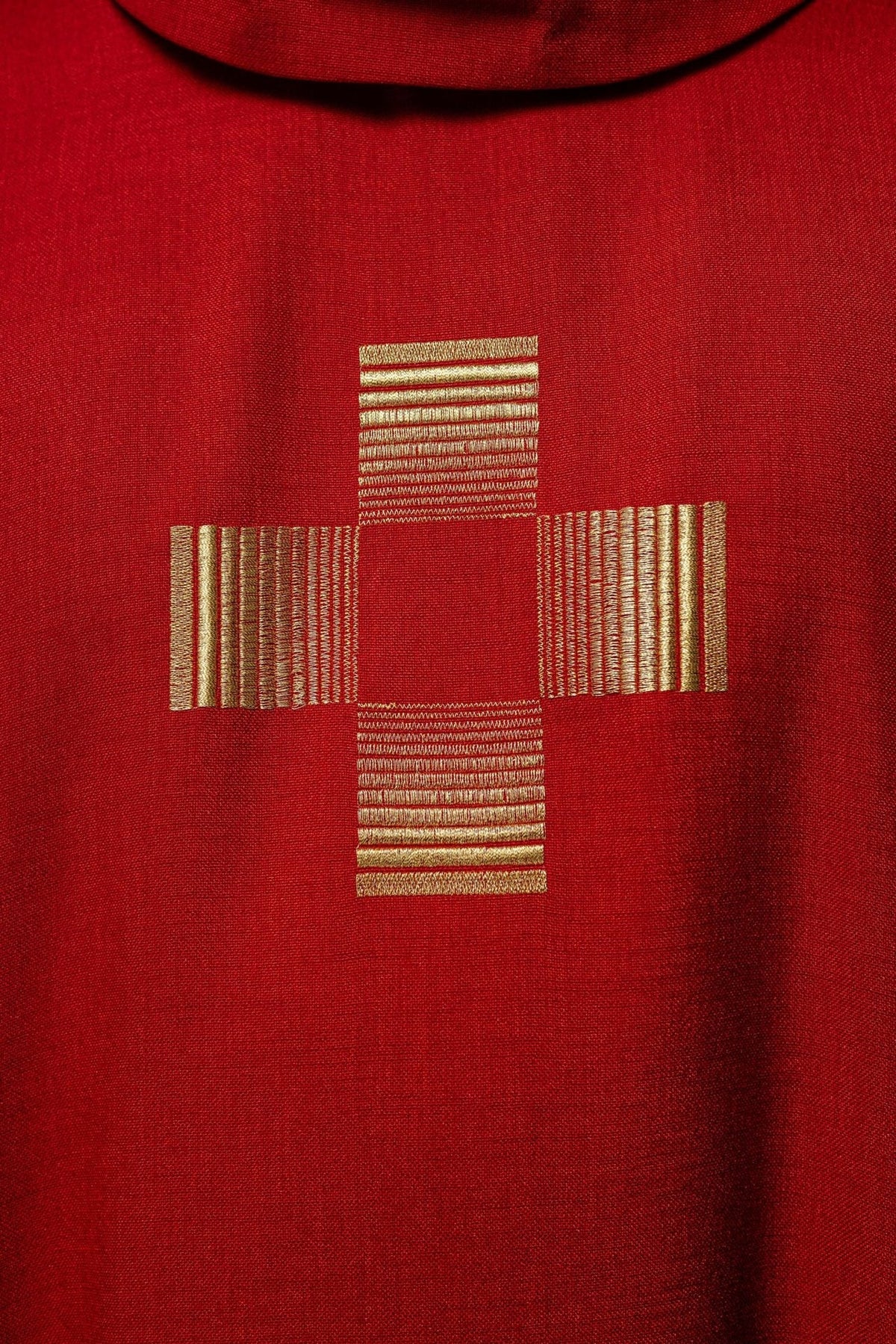 Red chasuble close-up of gold embroidered cross below the stand-up collar