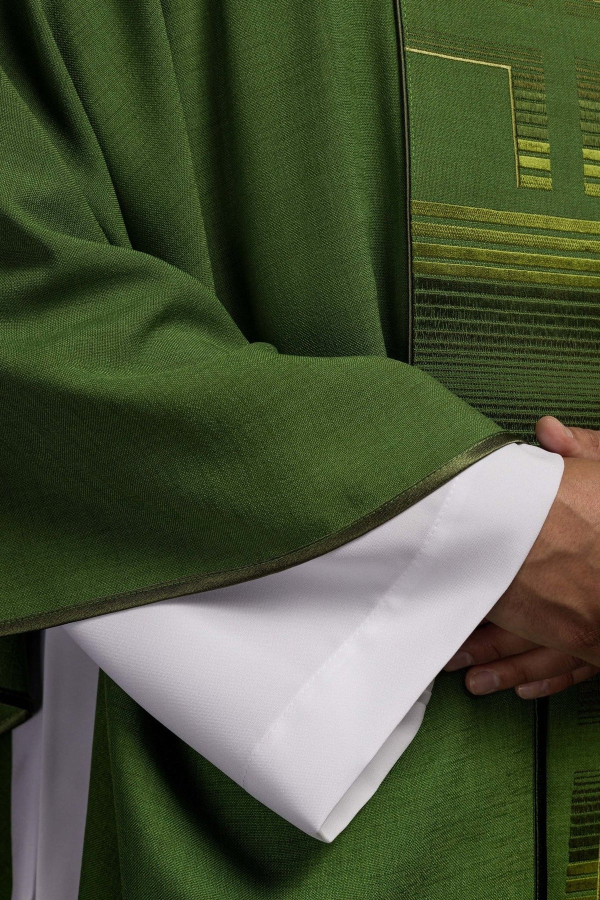 Green chasuble sleeve close-up with dark trim and white underlayer