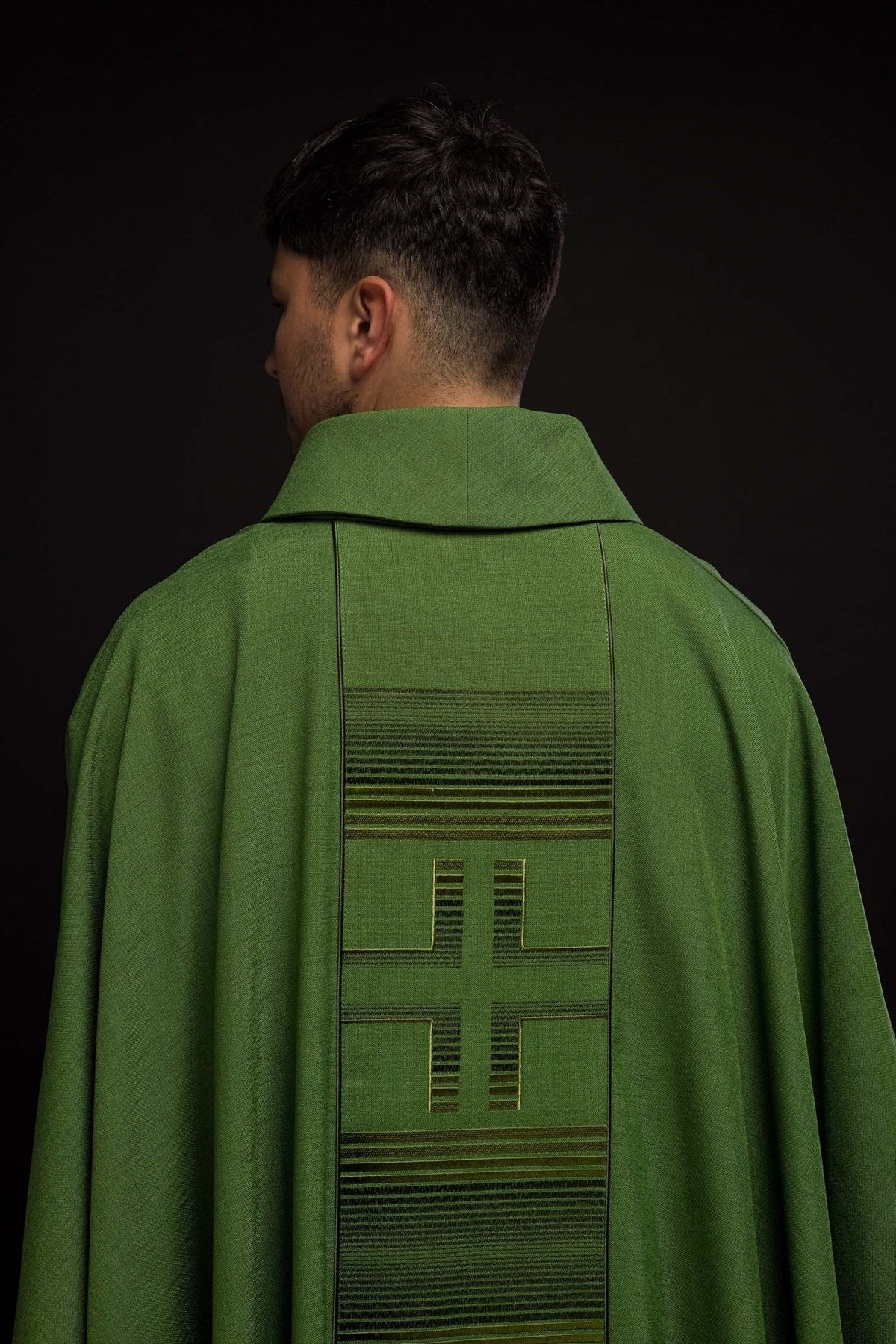 Green chasuble back view with central embroidered cross and horizontal trim