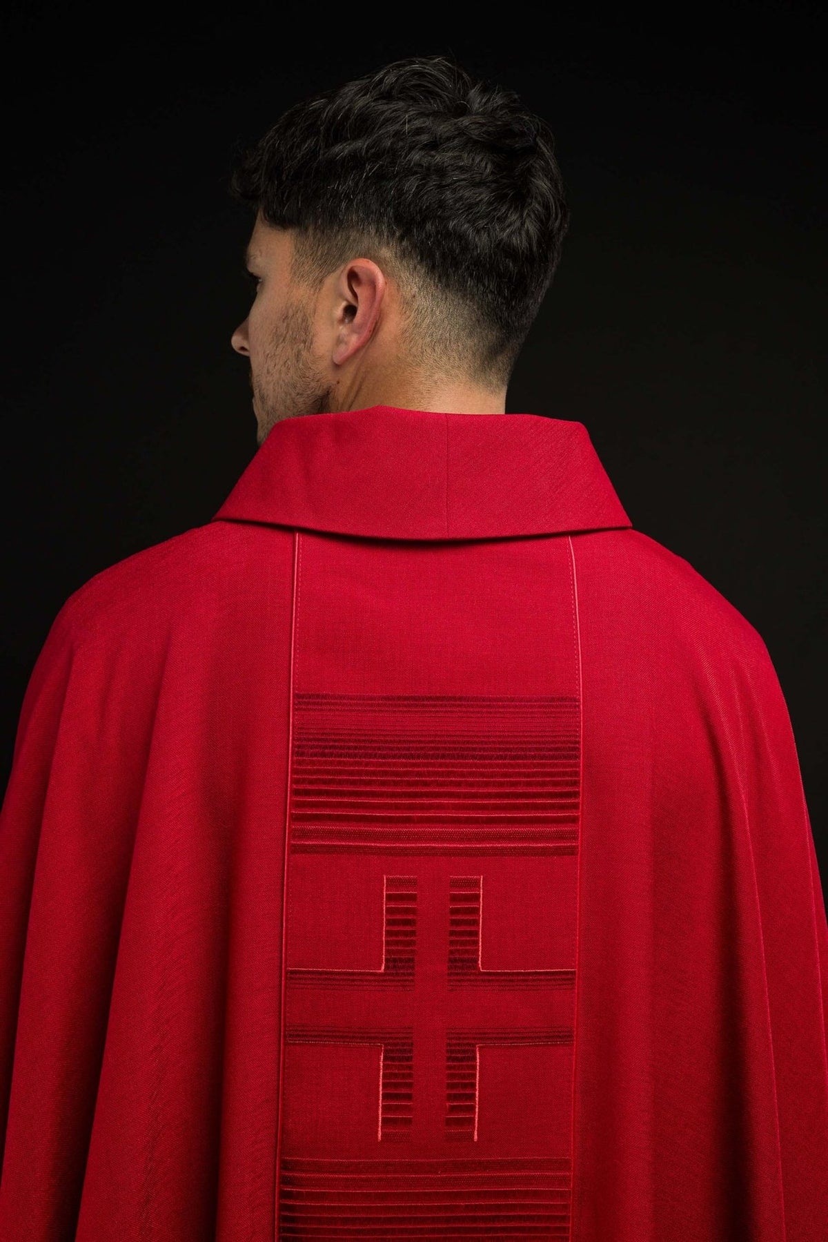 Red chasuble back view with embroidered crosses and horizontal trim