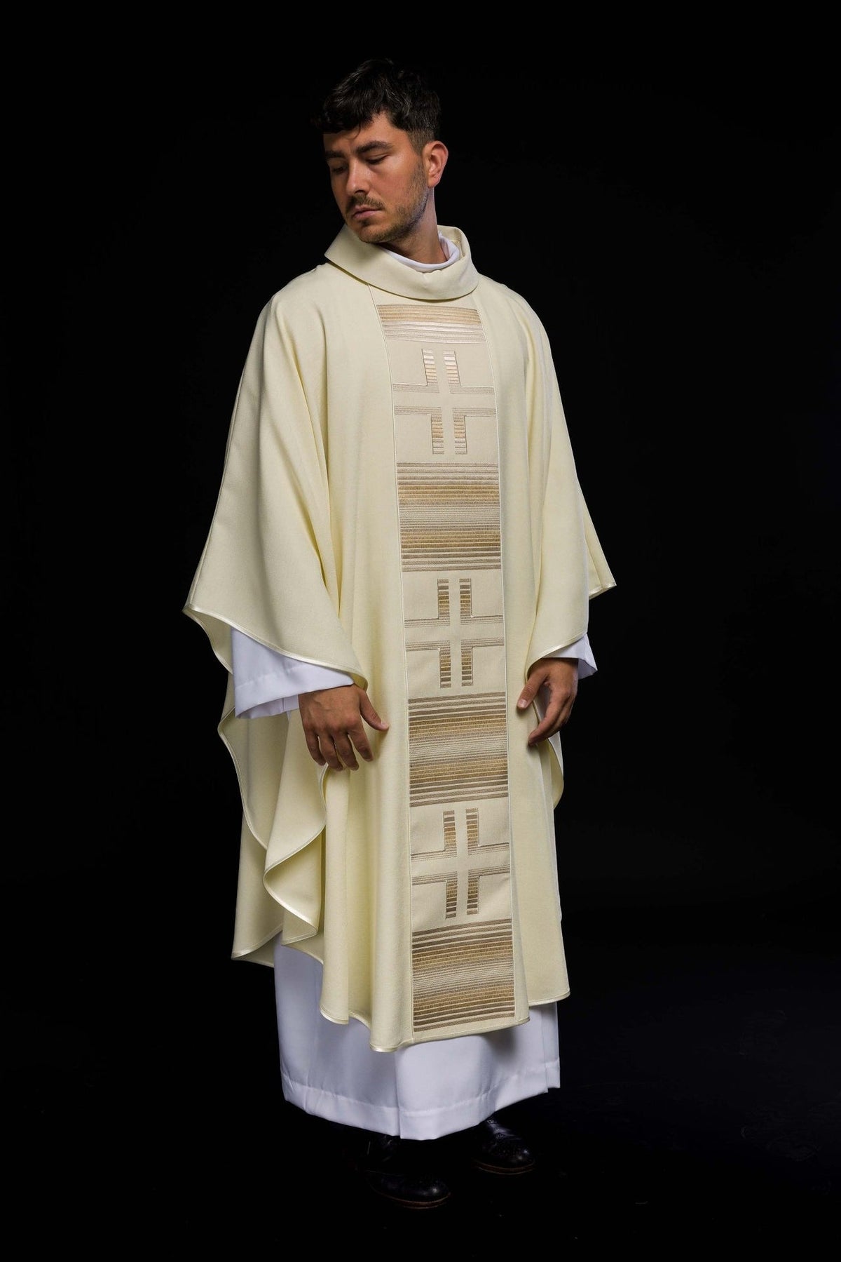Ecru chasuble worn, full front view with repeated cross embroidery and striped trim