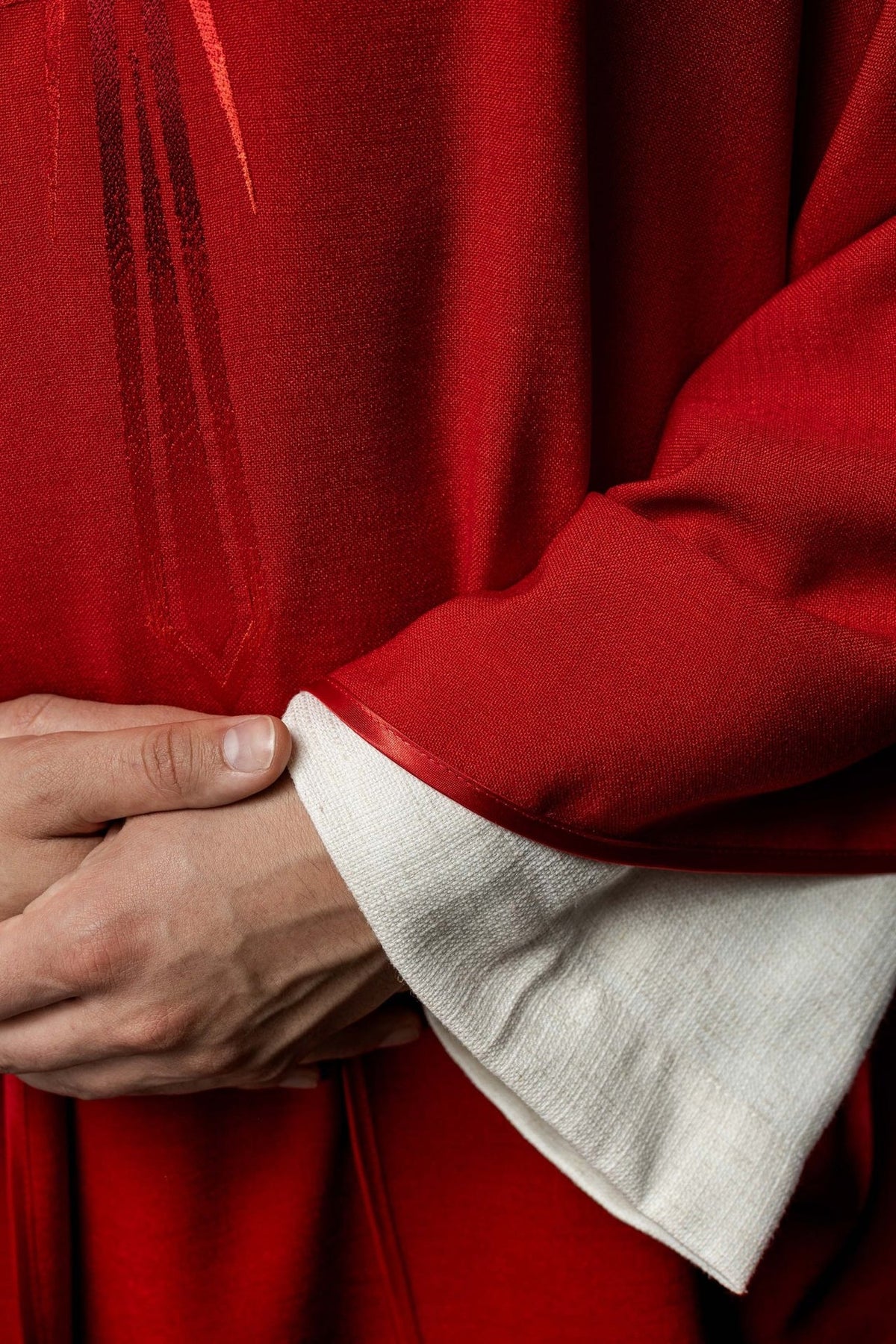 Red chasuble close-up showing embroidered cross and satin trim