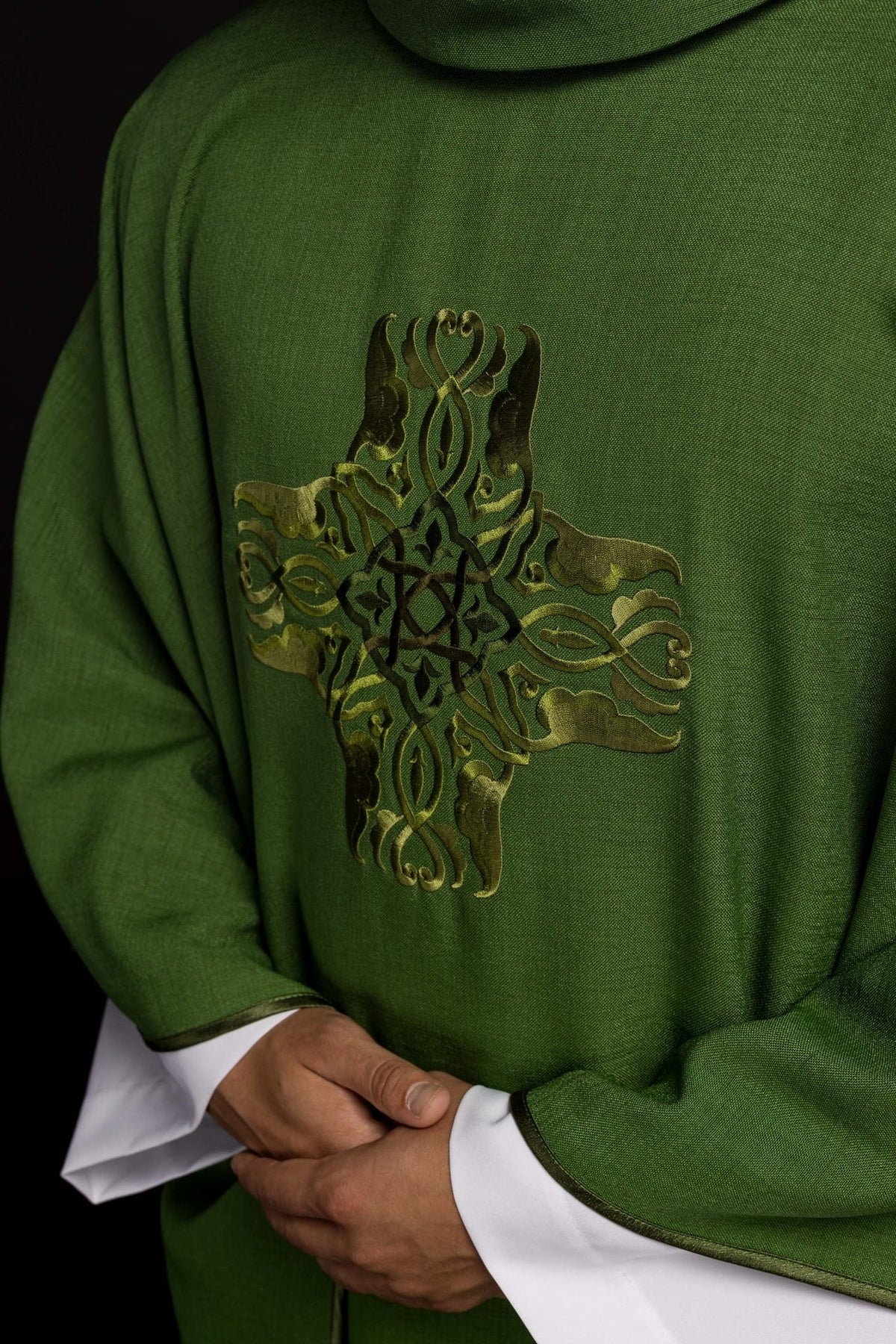 Green chasuble close-up showing ornate gold cross embroidery
