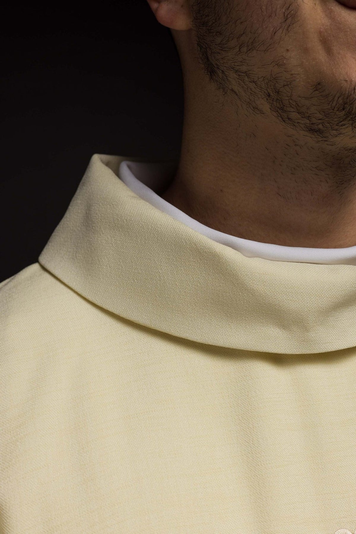Ecru chasuble detail showing satin trim and white sleeve opening