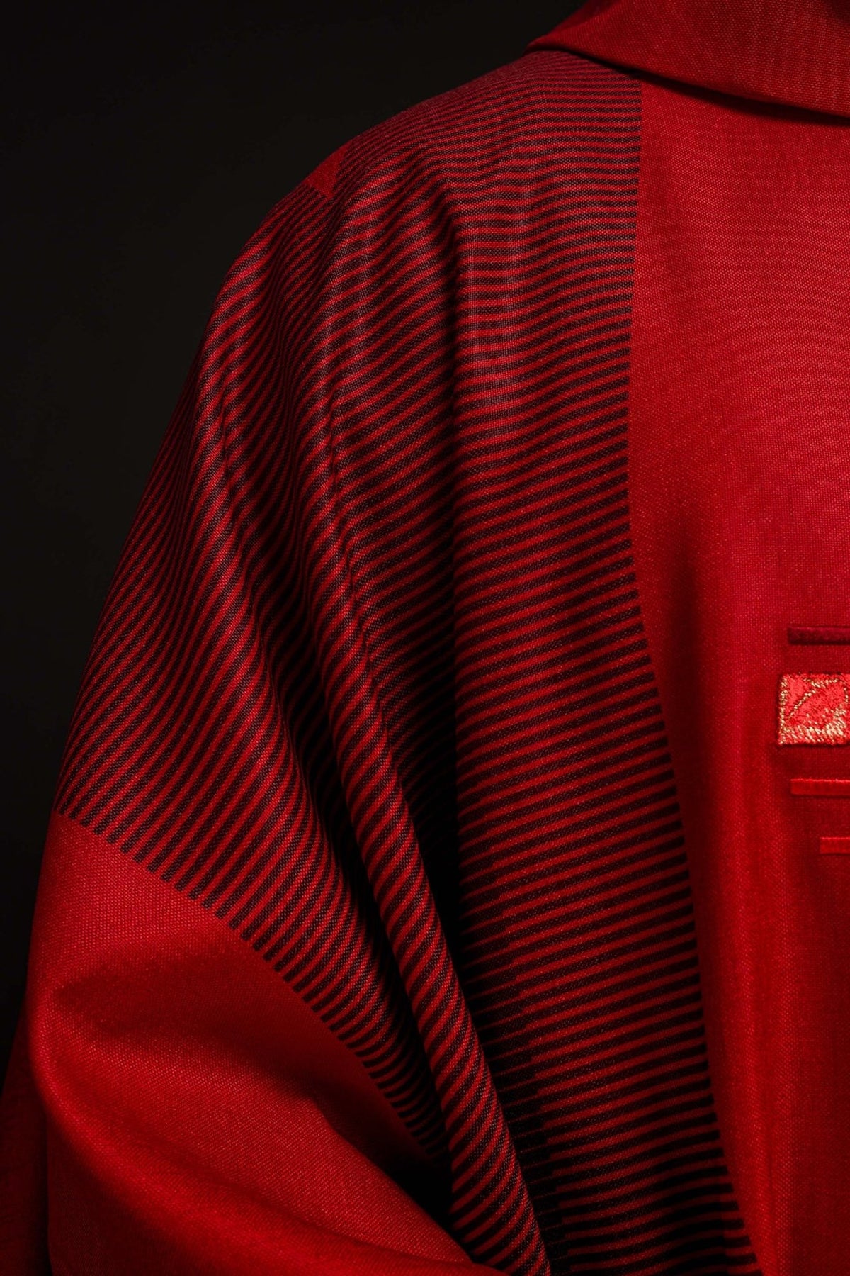 Red chasuble sleeve close-up with red trim and white cuff visible