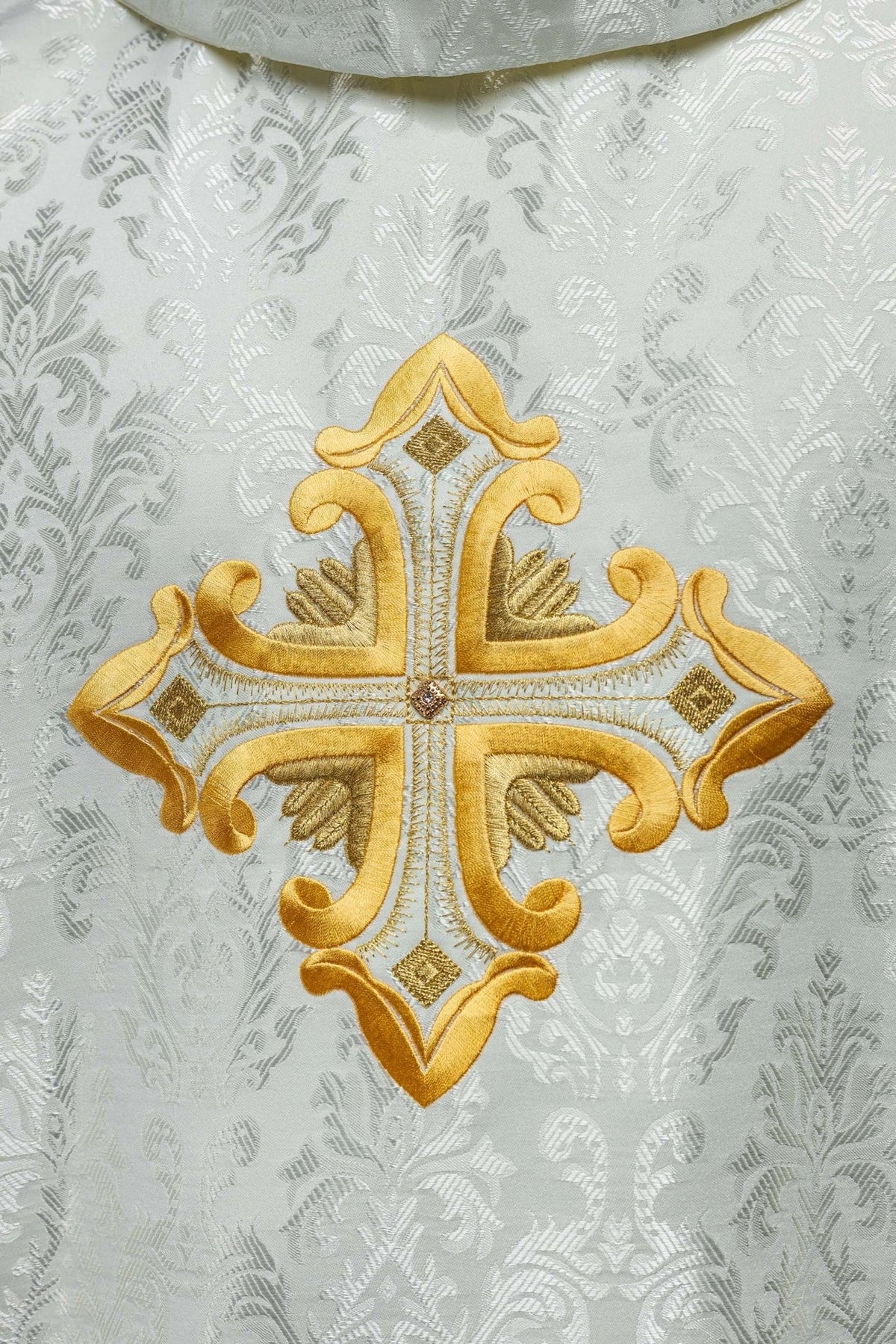 Ecru chasuble close-up of back gold cross embroidery on patterned fabric