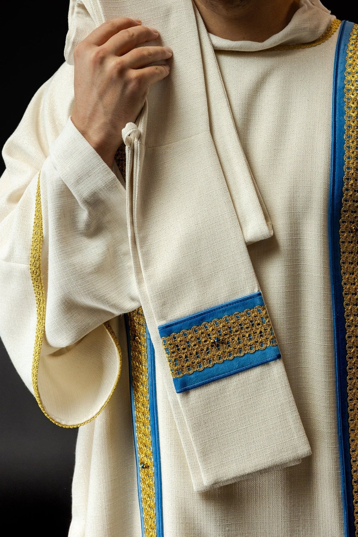 Handcrafted dalmatic front detail with white fabric, blue bands and gold embroidery