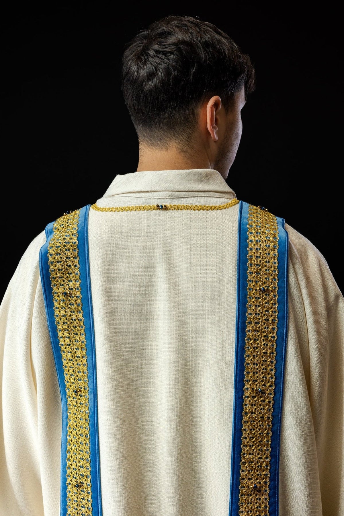 Handcrafted dalmatic back view with white fabric, blue bands and gold embroidery