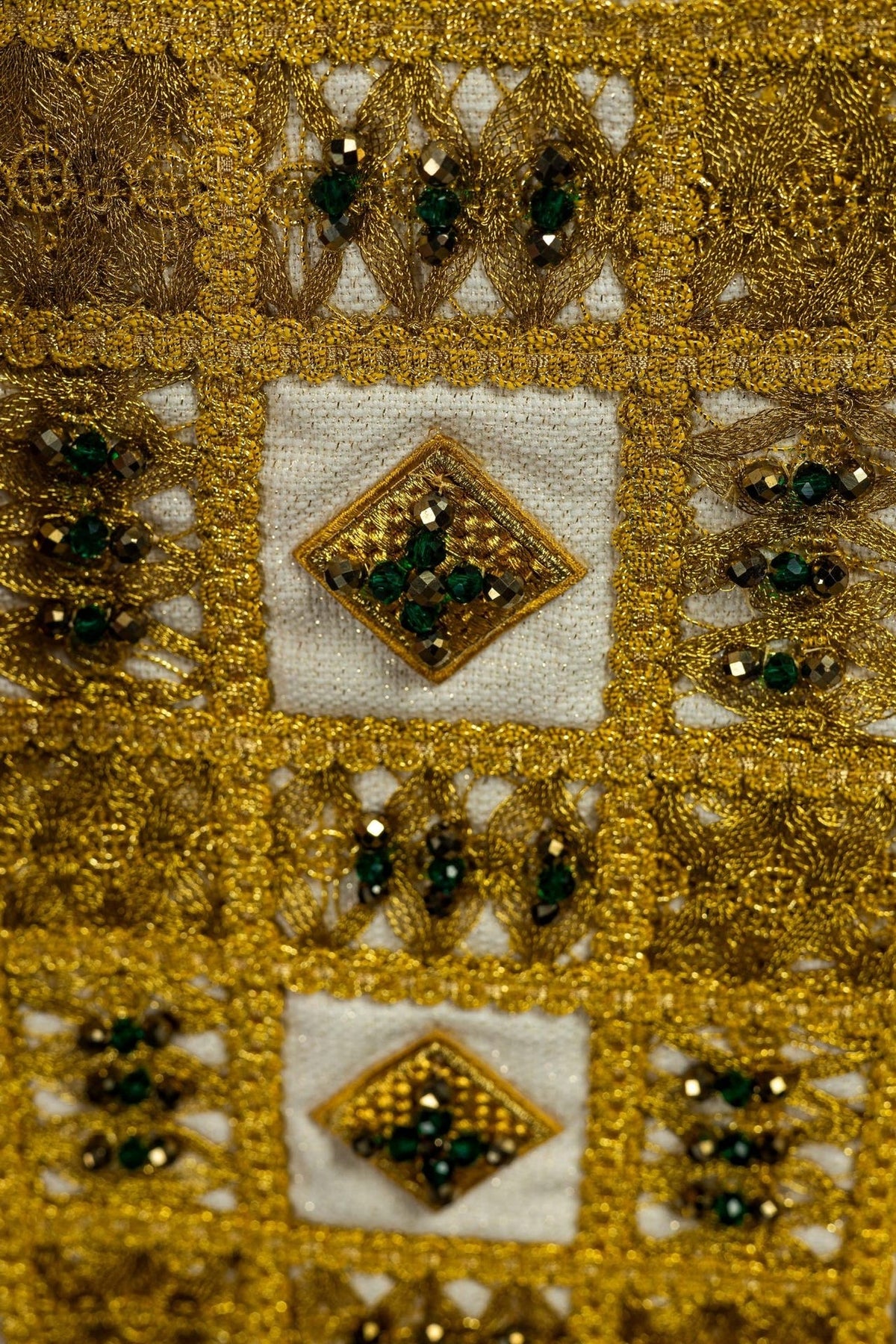 Stole embroidery close-up with gold thread, green stones and diamond motifs