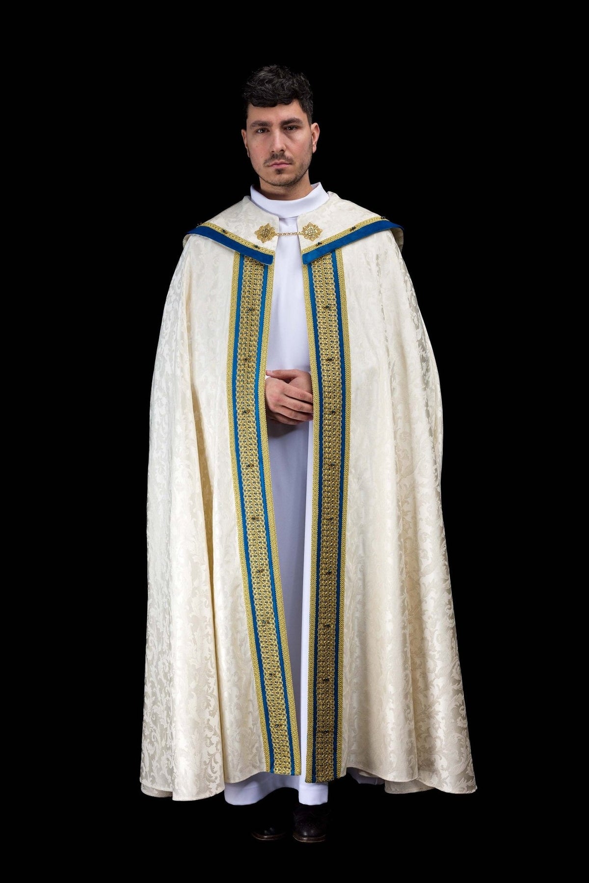 Marian cope front view in ecru jacquard fabric with blue velvet trim and gold embroidery