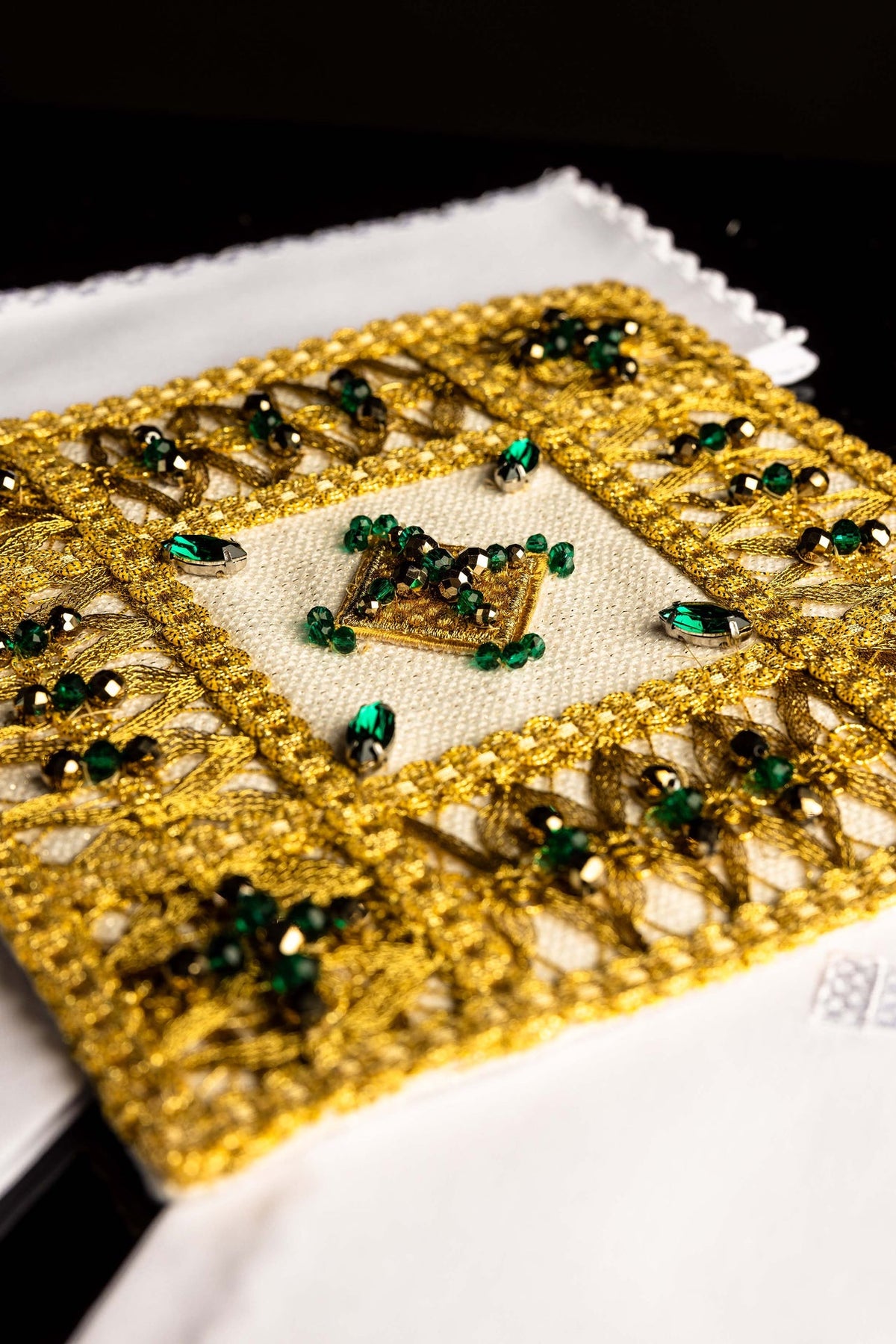 Altar linen set close-up showing gold lacework, green and black stones, and central square motif