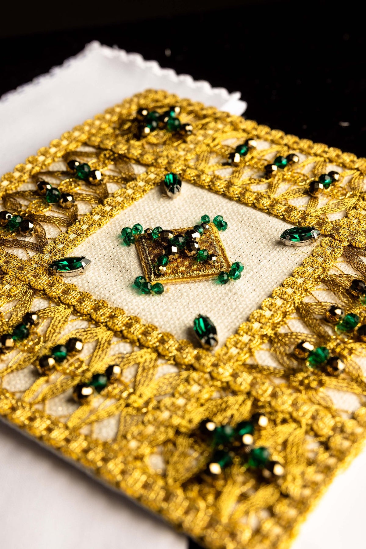 Altar linen set detail showing raised gold trim, green stones, and central embroidered square