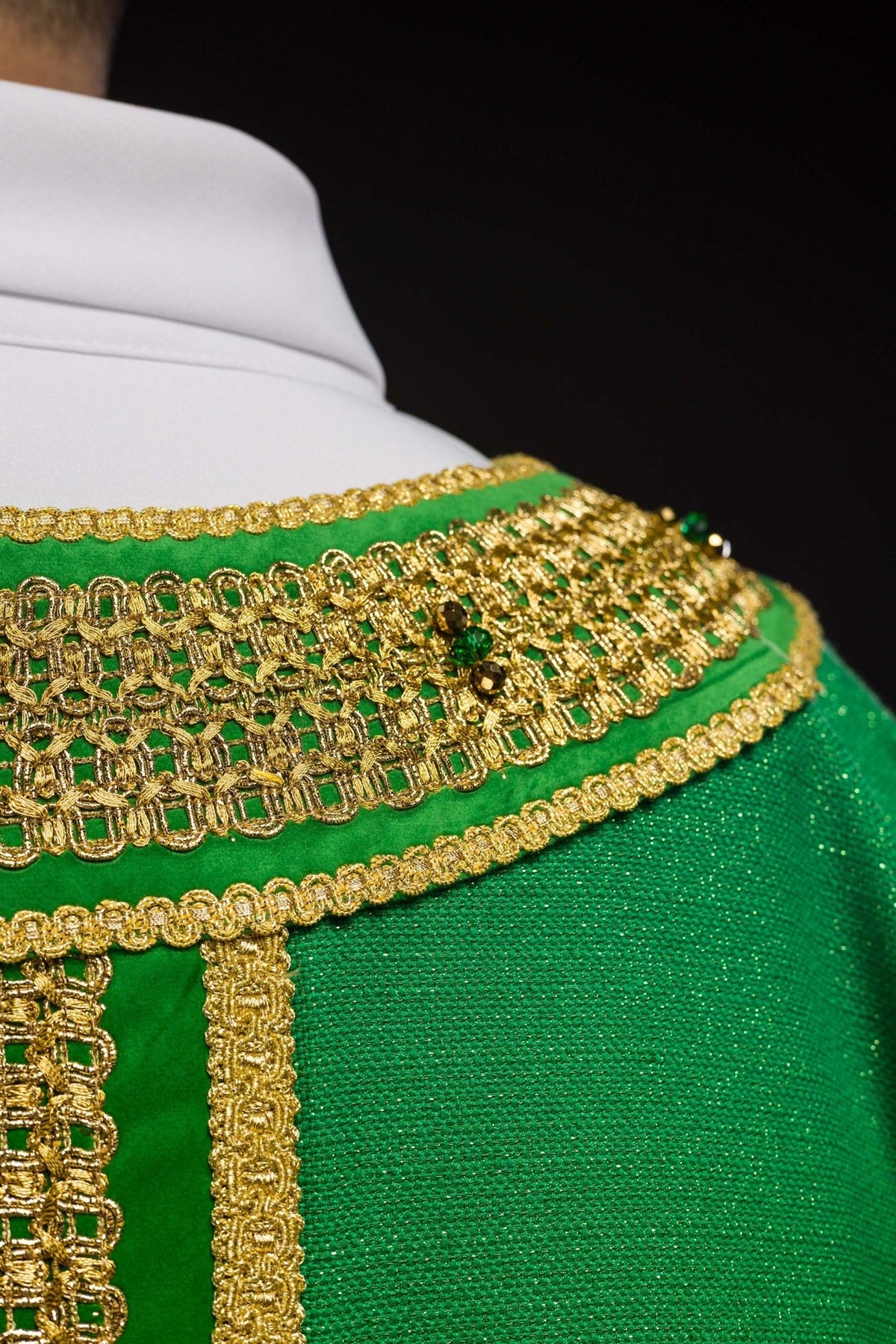 Green chasuble shoulder close-up with gold embroidery and natural stones