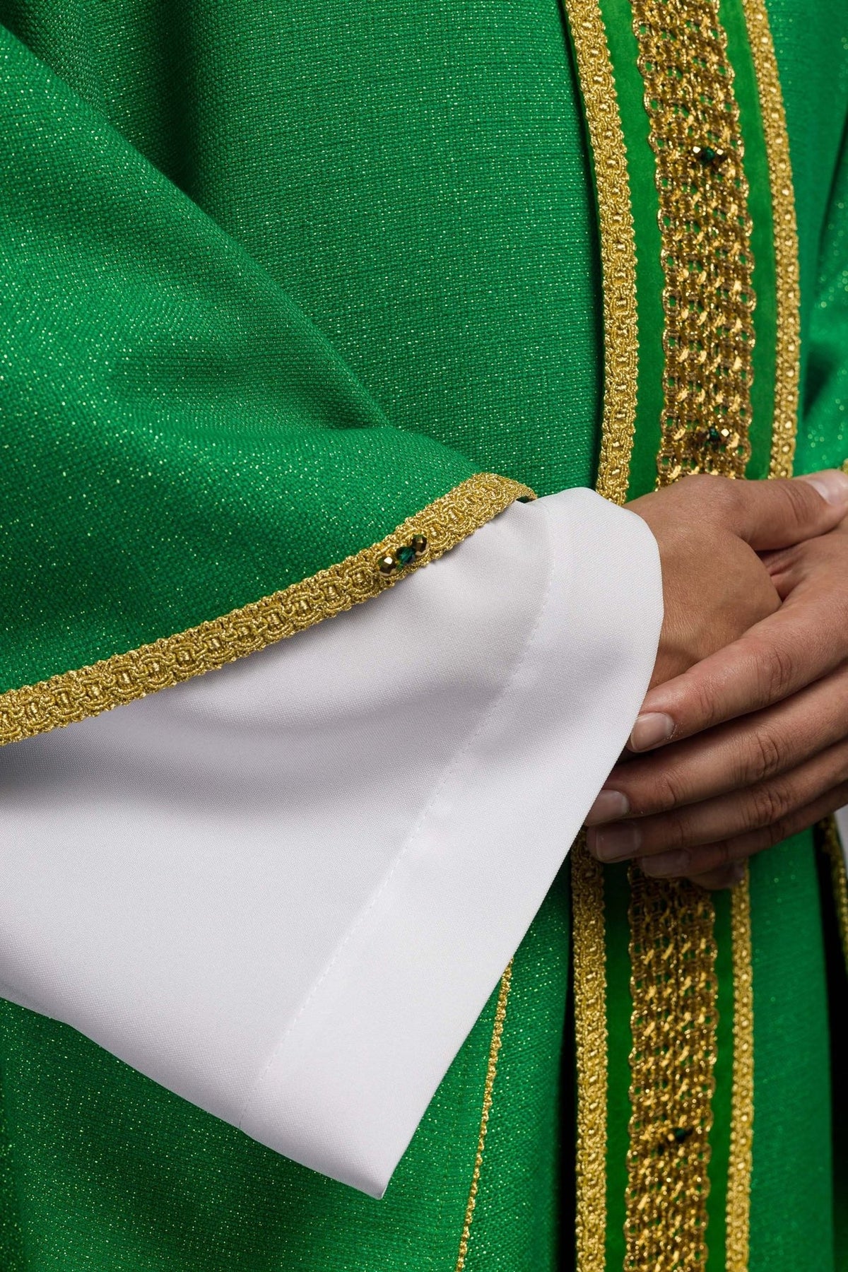 Green chasuble sleeve close-up with gold trim and green stone accents