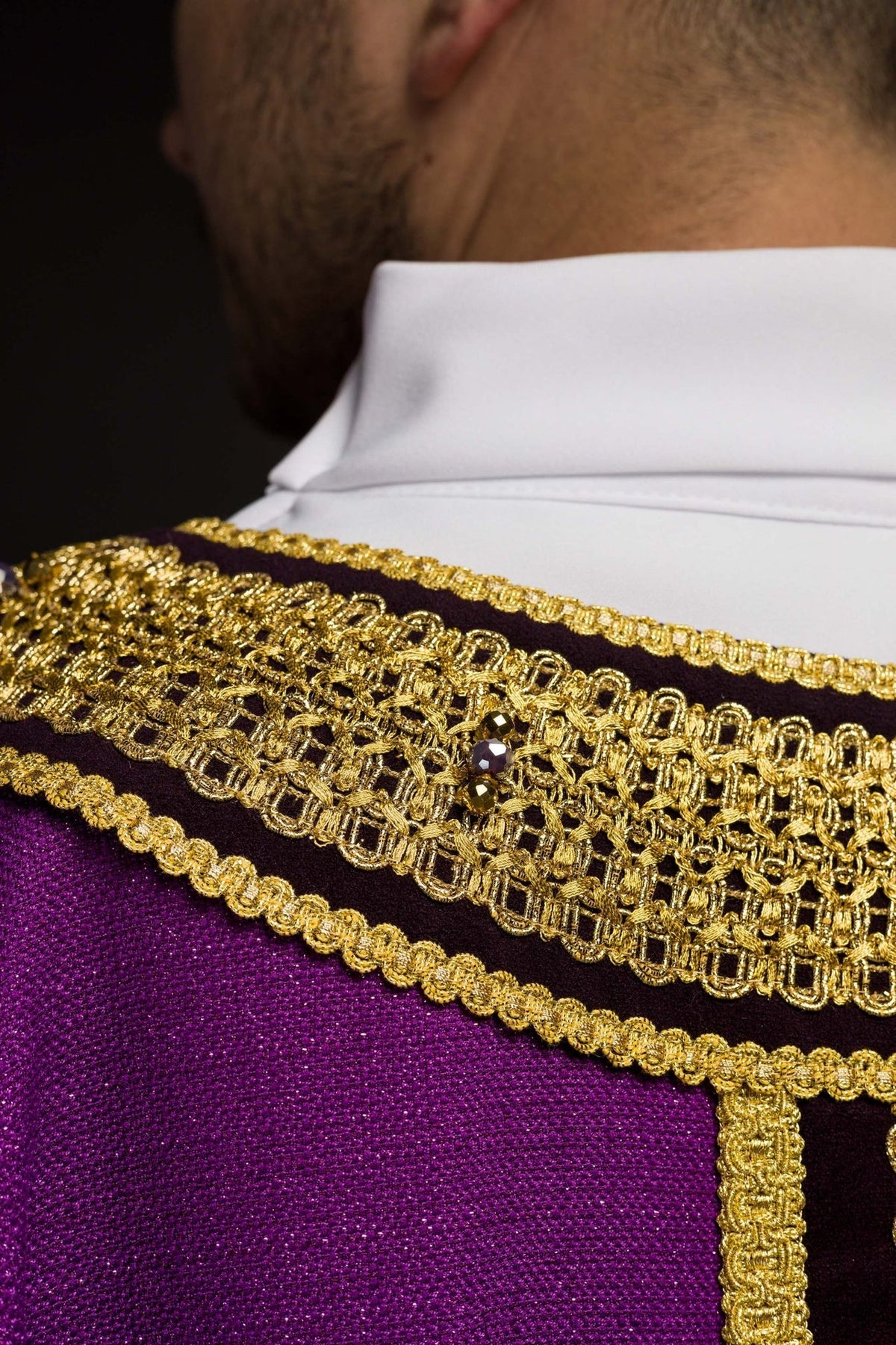 Handcrafted chasuble close-up in purple with gold embroidery, black orphrey and natural stones