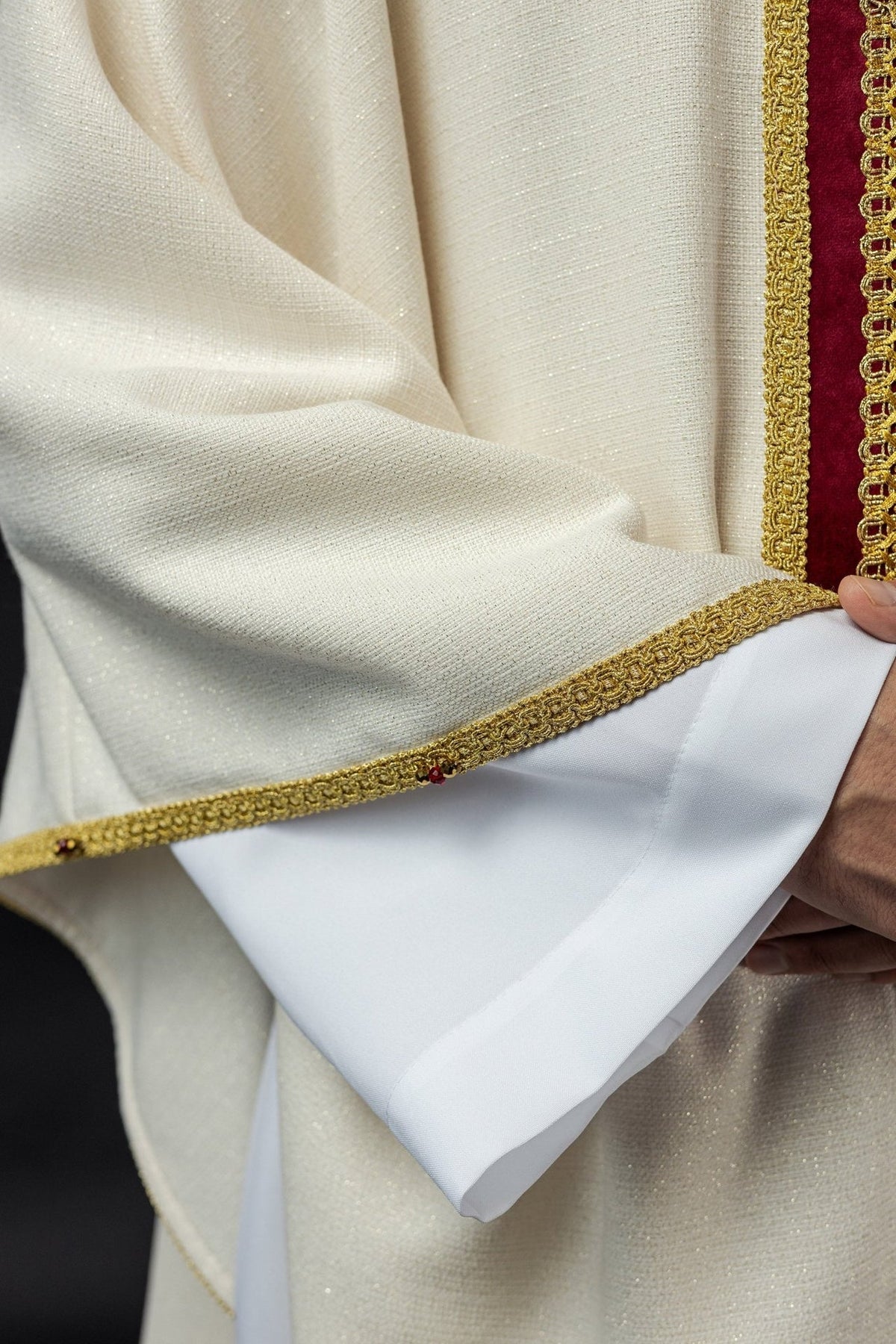 Close-up of the ivory chasuble fabric and gold-trimmed hem