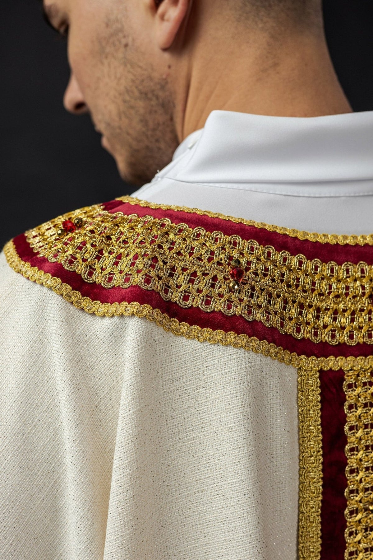 Chasuble shoulder close-up with red velvet, gold embroidery and natural stones