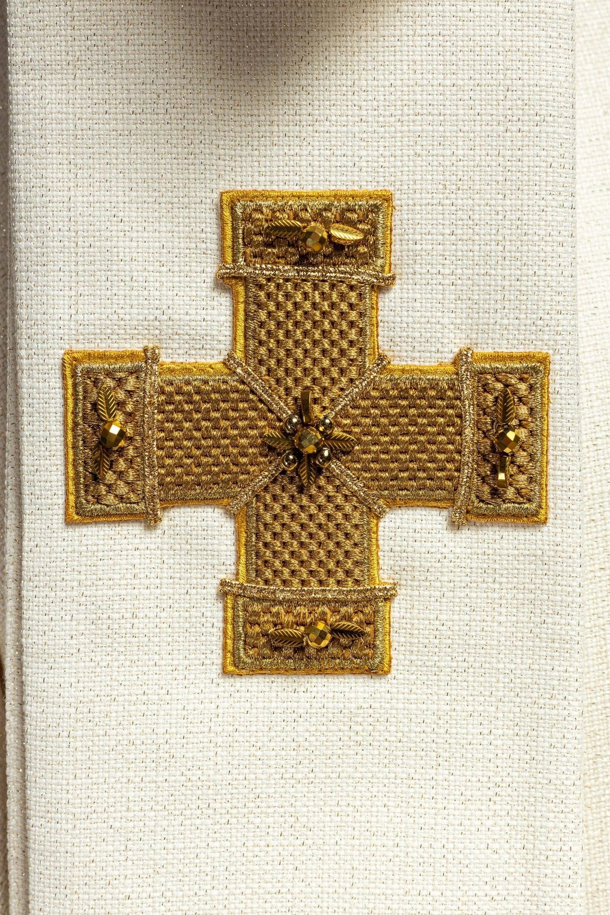 Handcrafted chasuble close-up with gold cross embroidery and natural stones