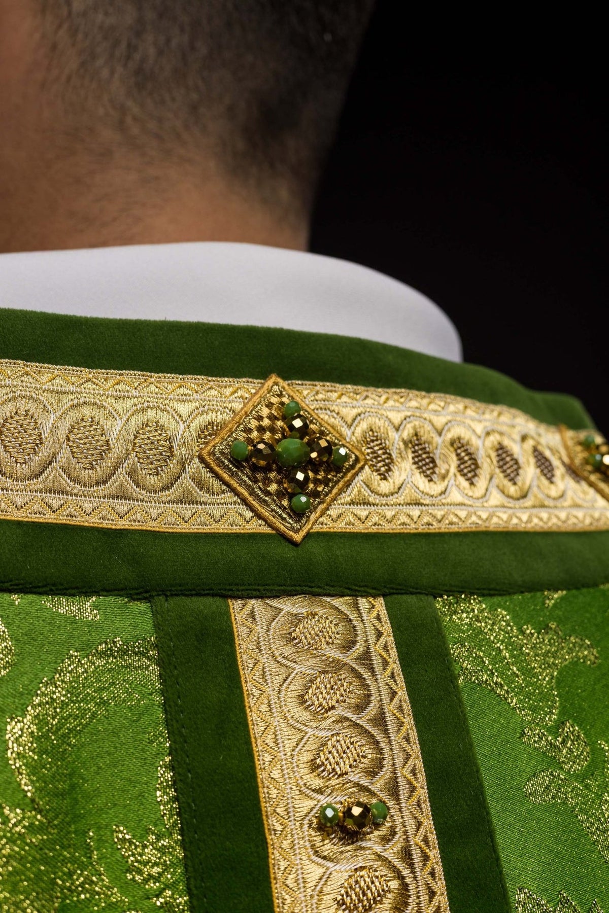Green handcrafted chasuble close-up with gold embroidery and natural stones on the orphrey