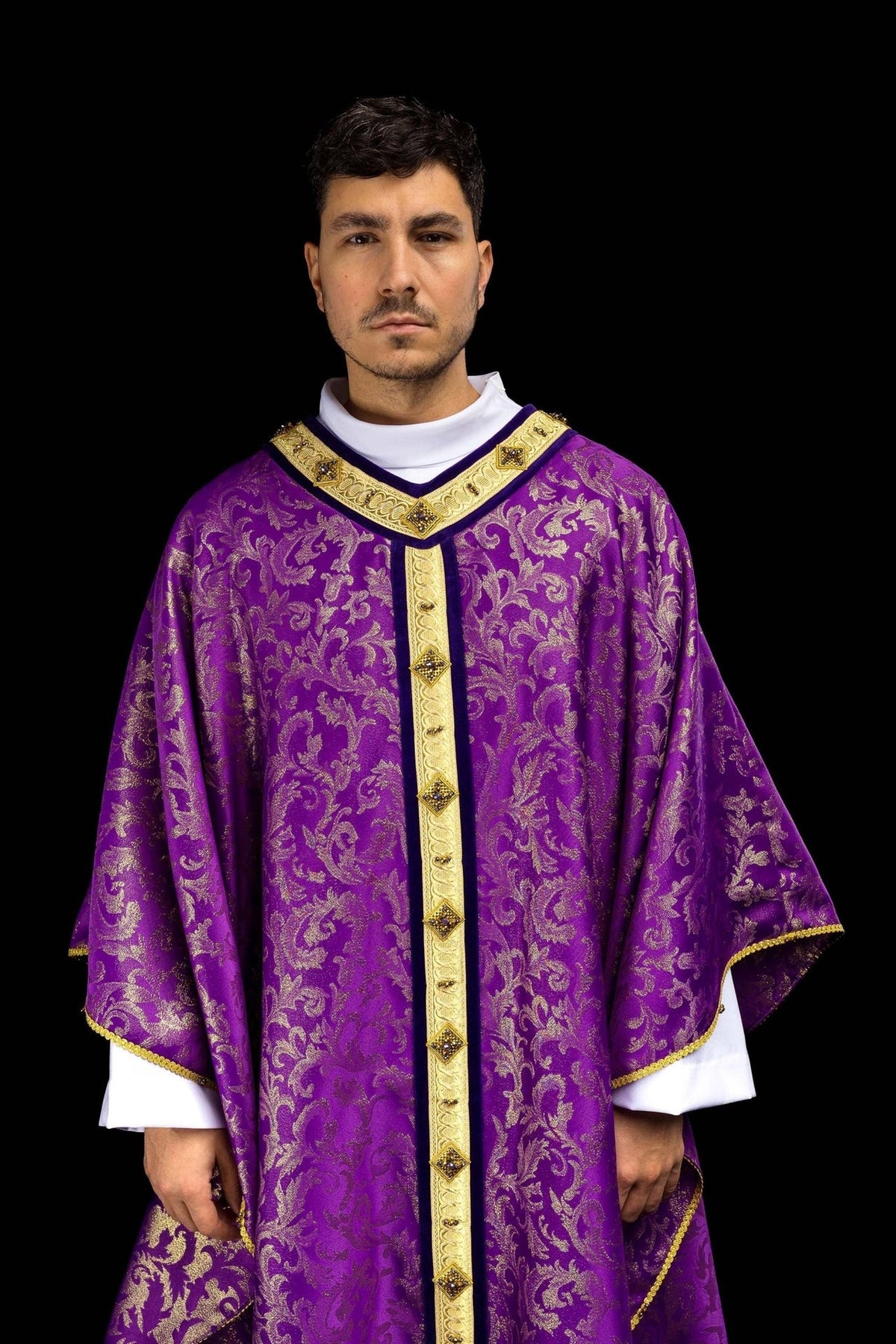 Purple chasuble close-up showing gold jacquard motifs and jeweled orphrey