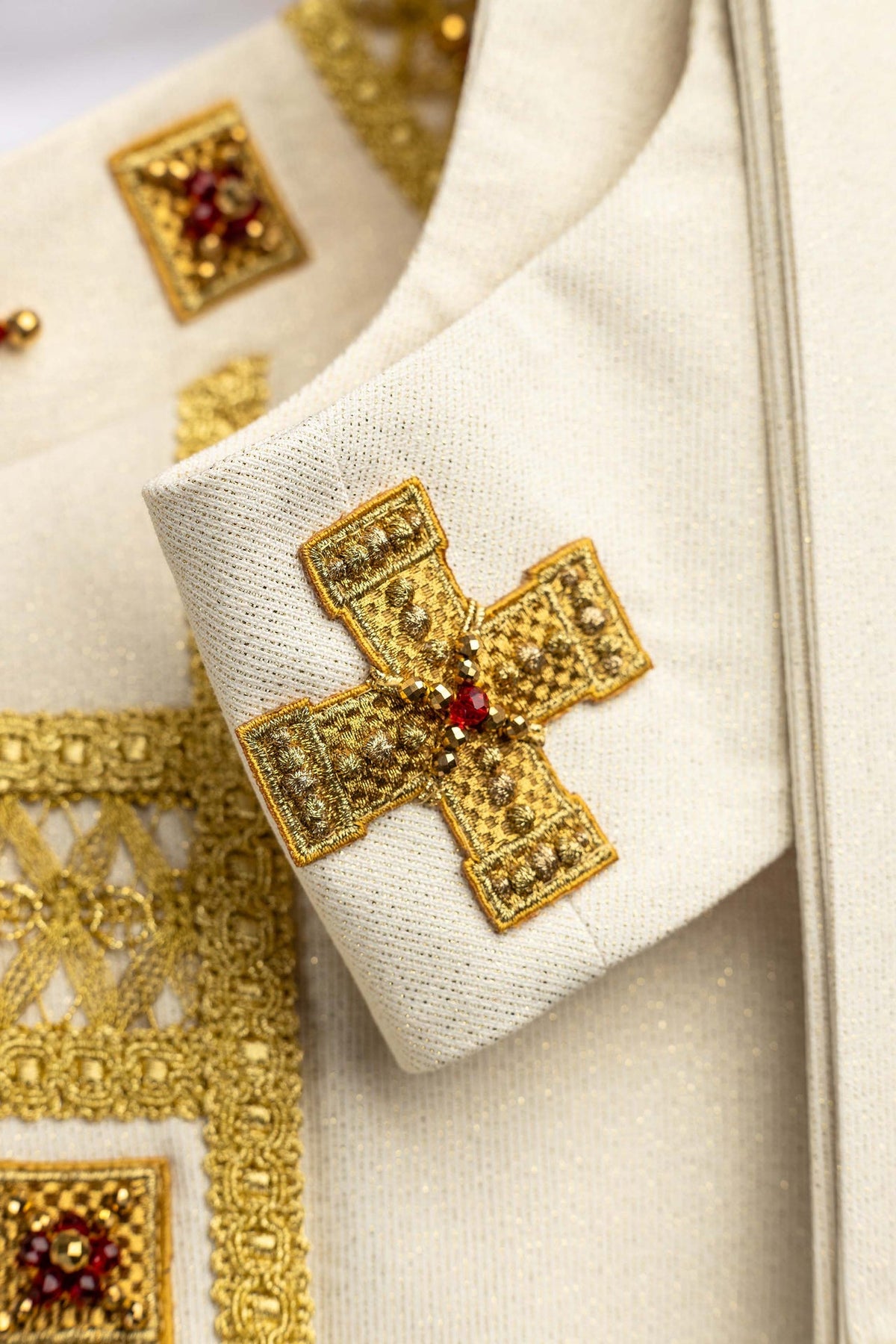 Handcrafted chasuble with natural stones, close-up of gold cross and white fabric