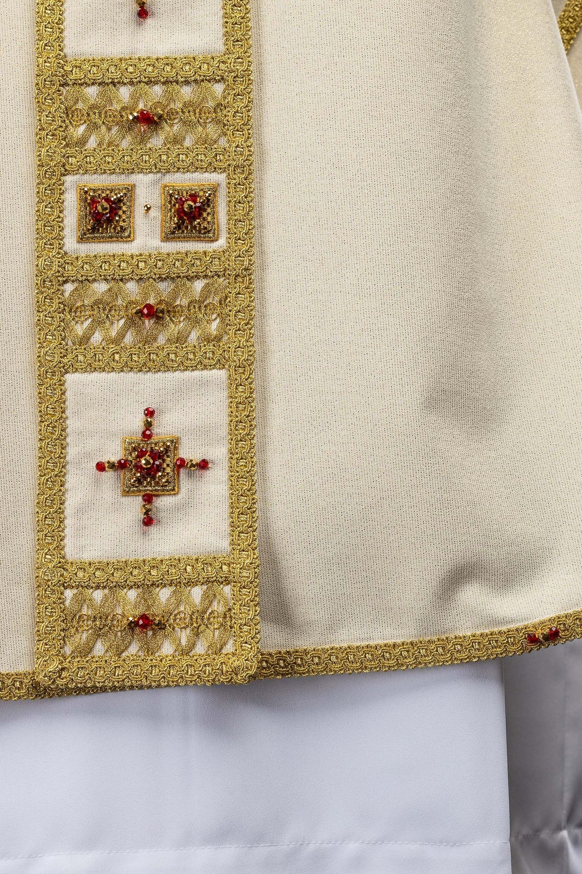 Handcrafted chasuble sleeve detail with gold edging and red stone accents