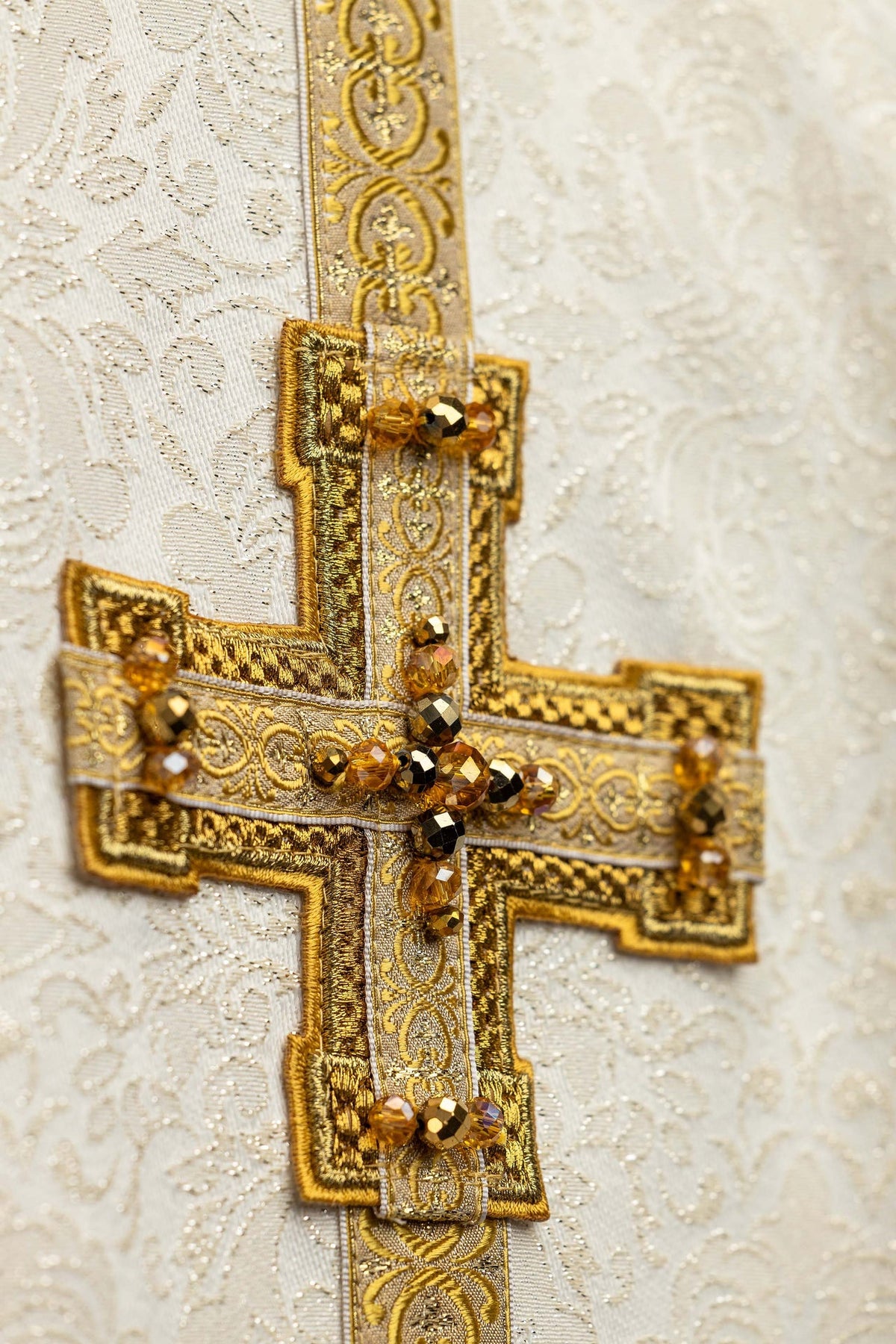 Handcrafted chasuble with natural stones, close-up of gold embroidered cross and beaded details
