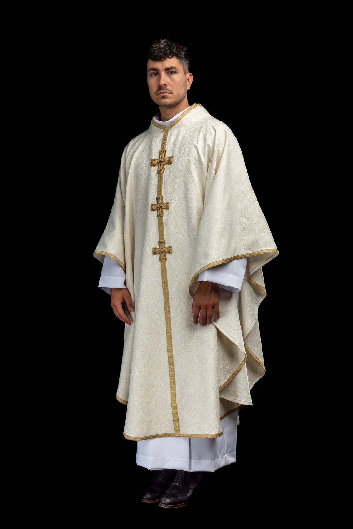 Ivory chasuble worn full length with gold trim and three jeweled crosses