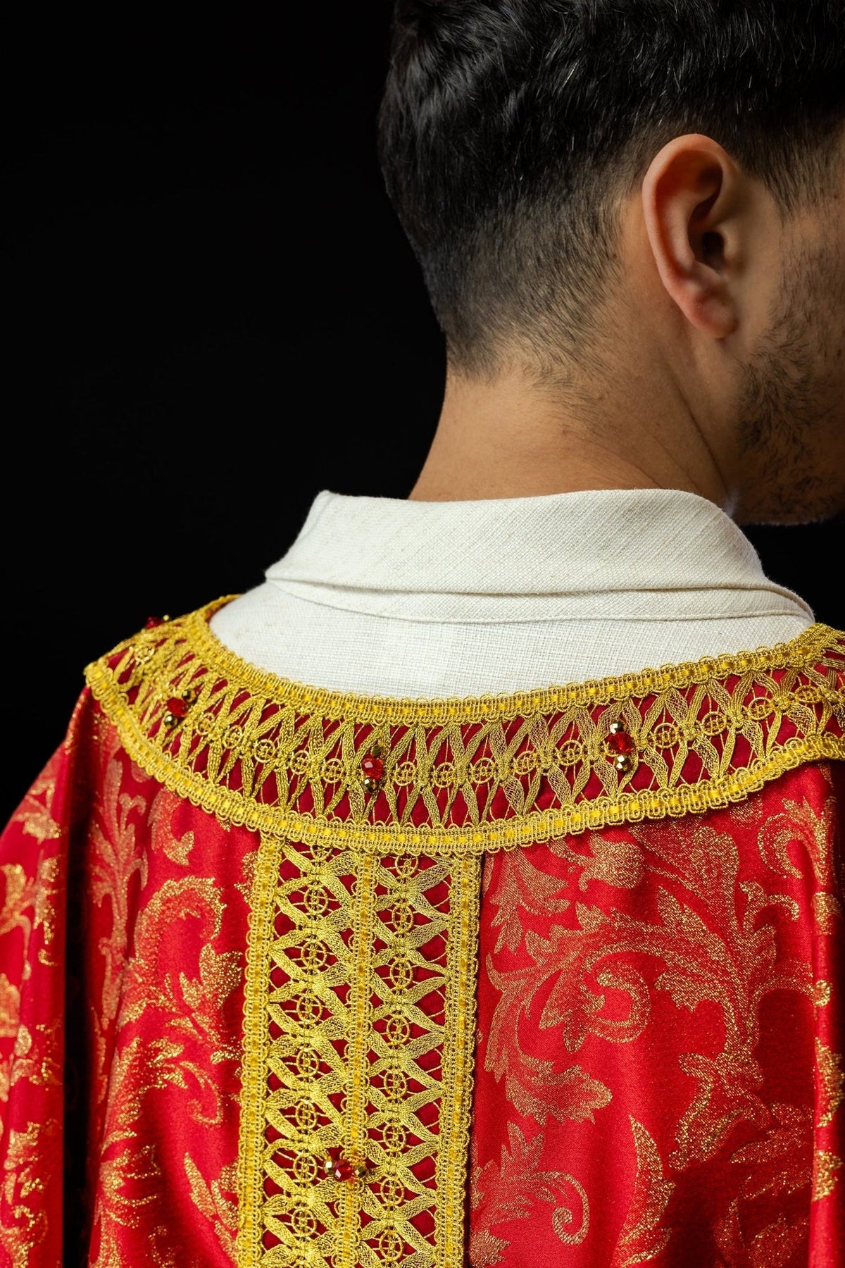Red chasuble back close-up showing gold collar, orphrey and natural stones