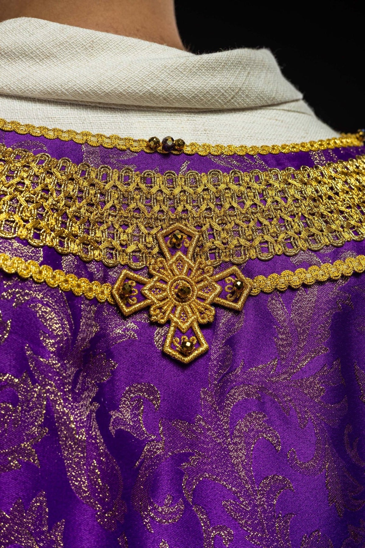Handcrafted Purple Chasuble close-up with gold cross embroidery and natural stones