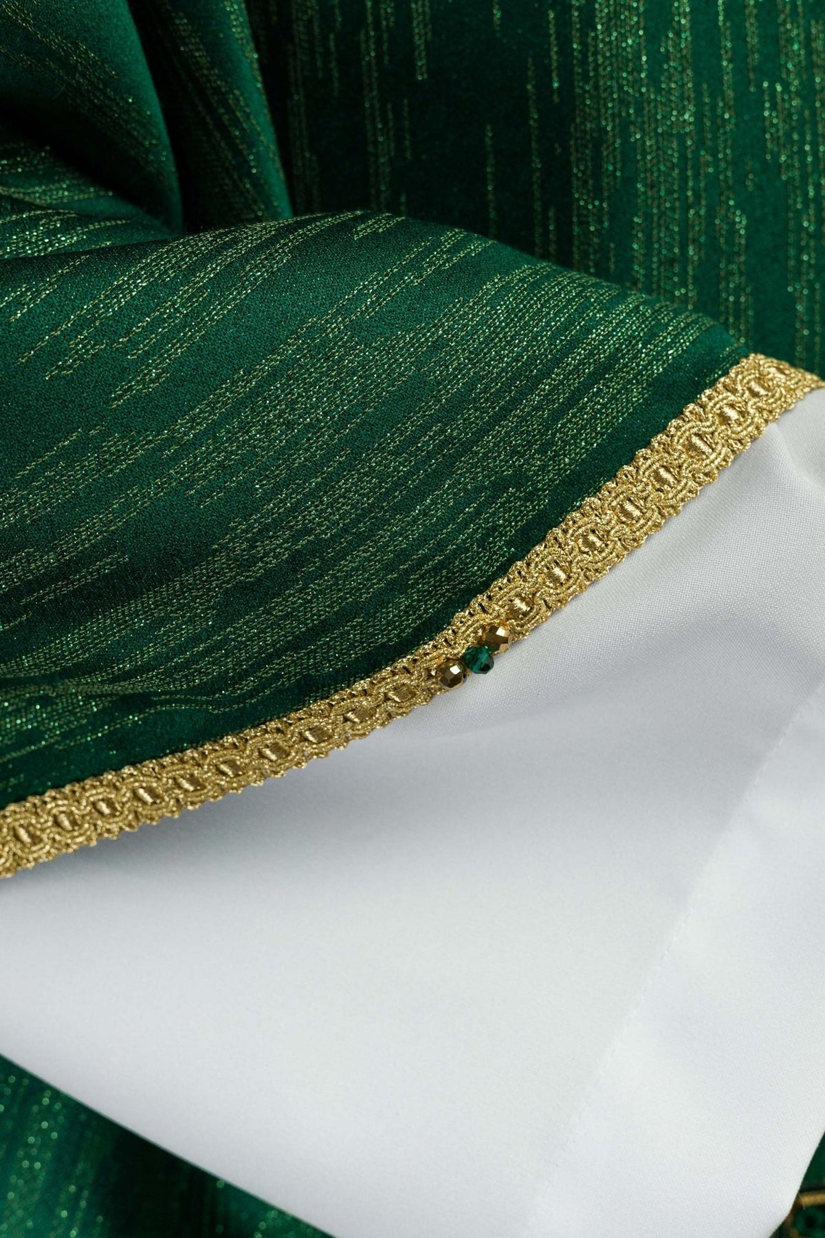 Green chasuble fabric close-up with gold vertical threads and trim