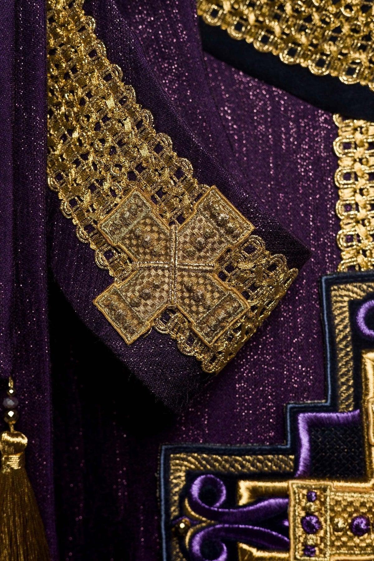 Purple chasuble detail showing gold tassel and cross embroidery