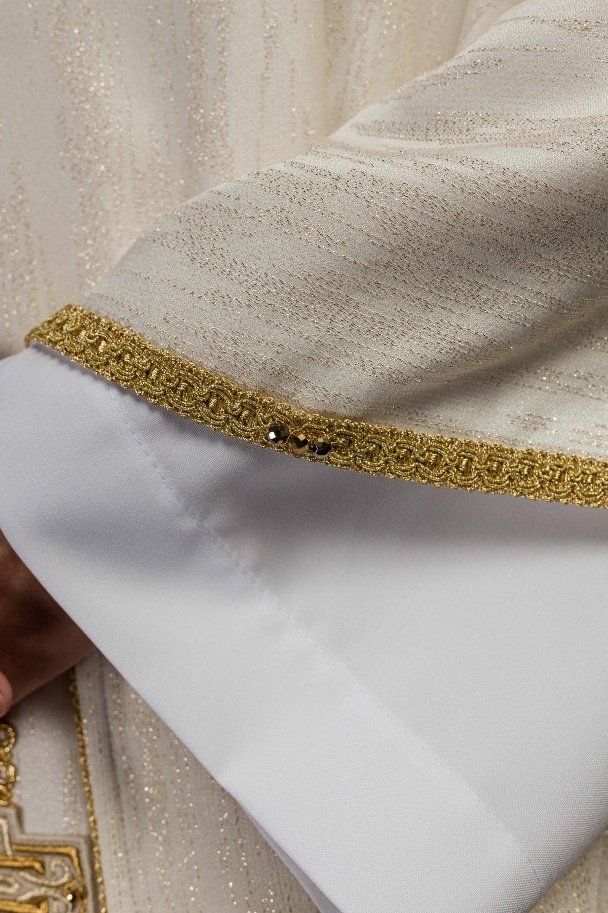 Chasuble sleeve edge close-up with gold trim and natural stones