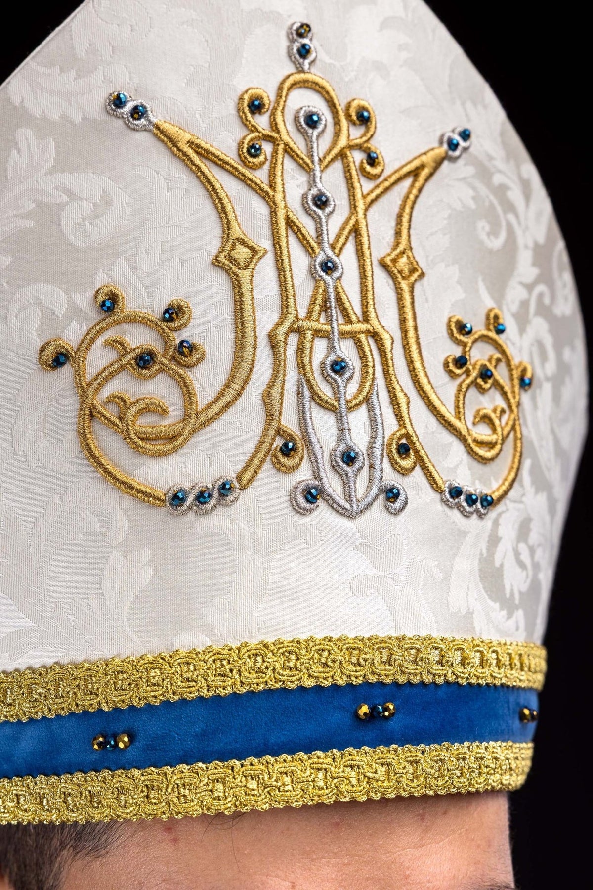Close-up of Marian miter showing gold Marian symbol embroidery and blue natural stones
