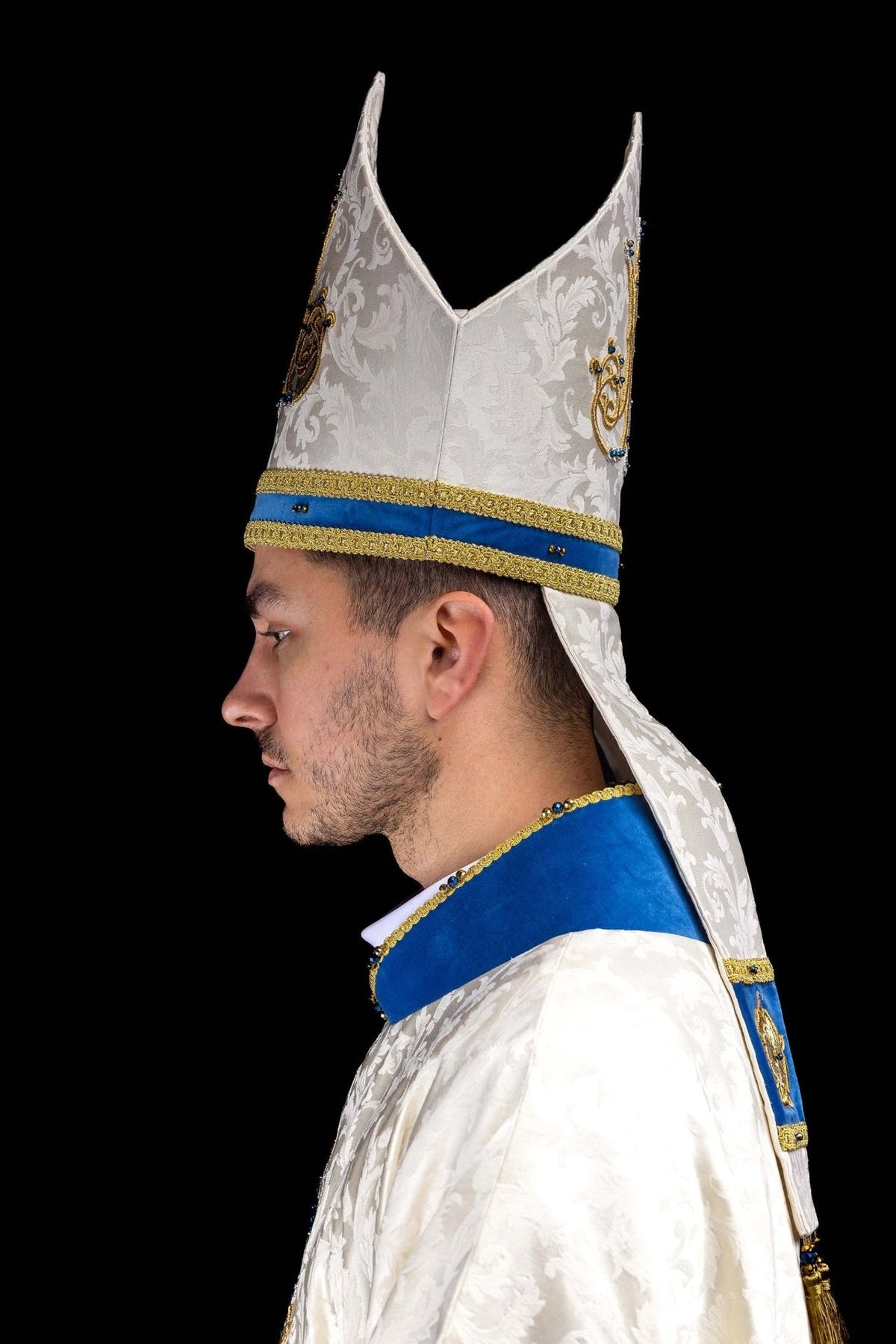 Marian miter in back view with ecru patterned fabric, blue band and gold trim