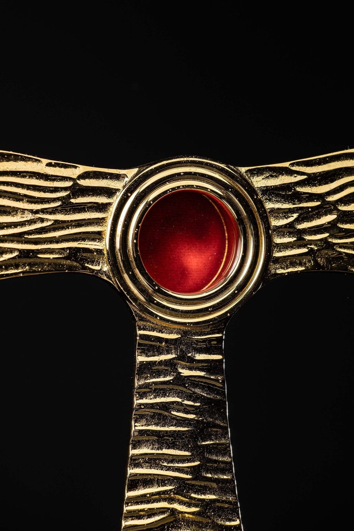 Tau cross reliquary detail showing concentric brass rings around the red repository
