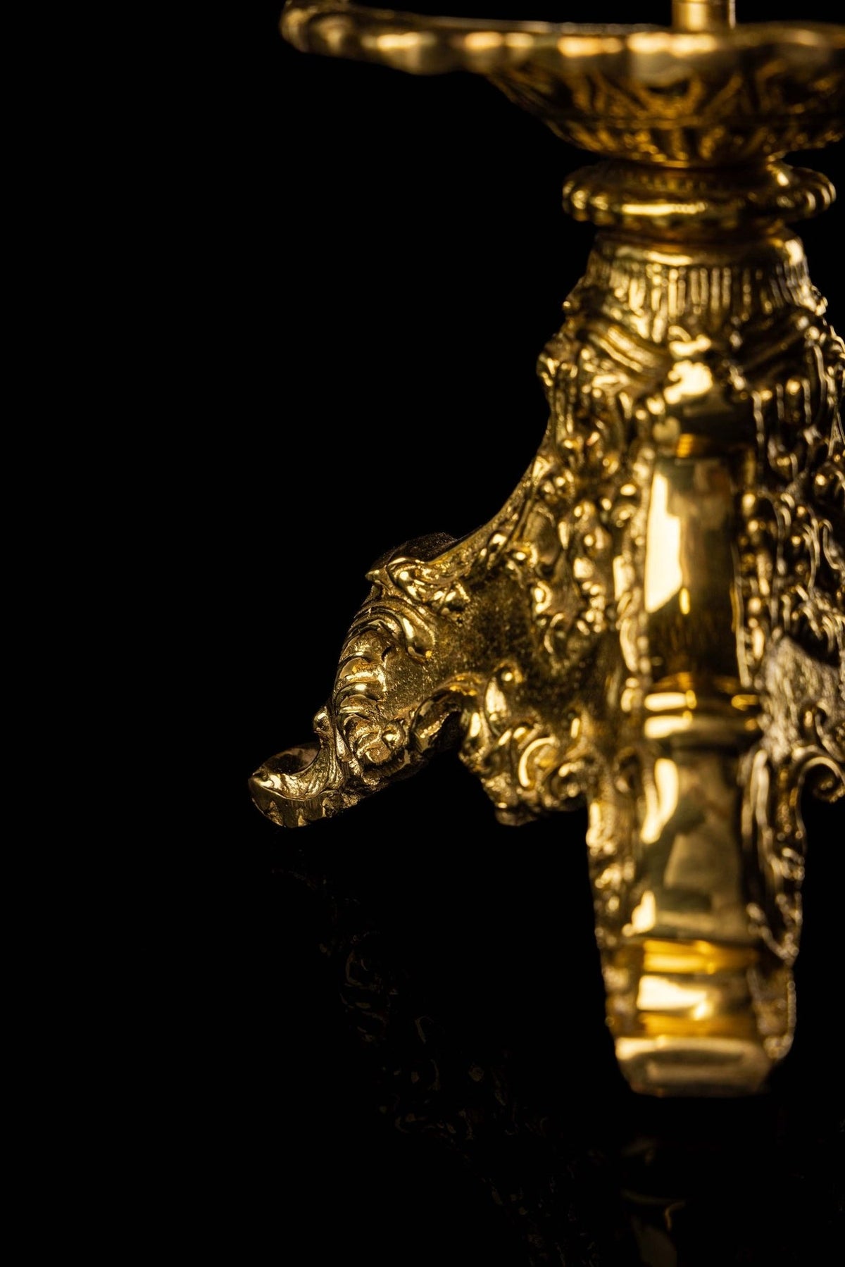 Brass candlestick base close-up with ornate scrollwork and raised foot