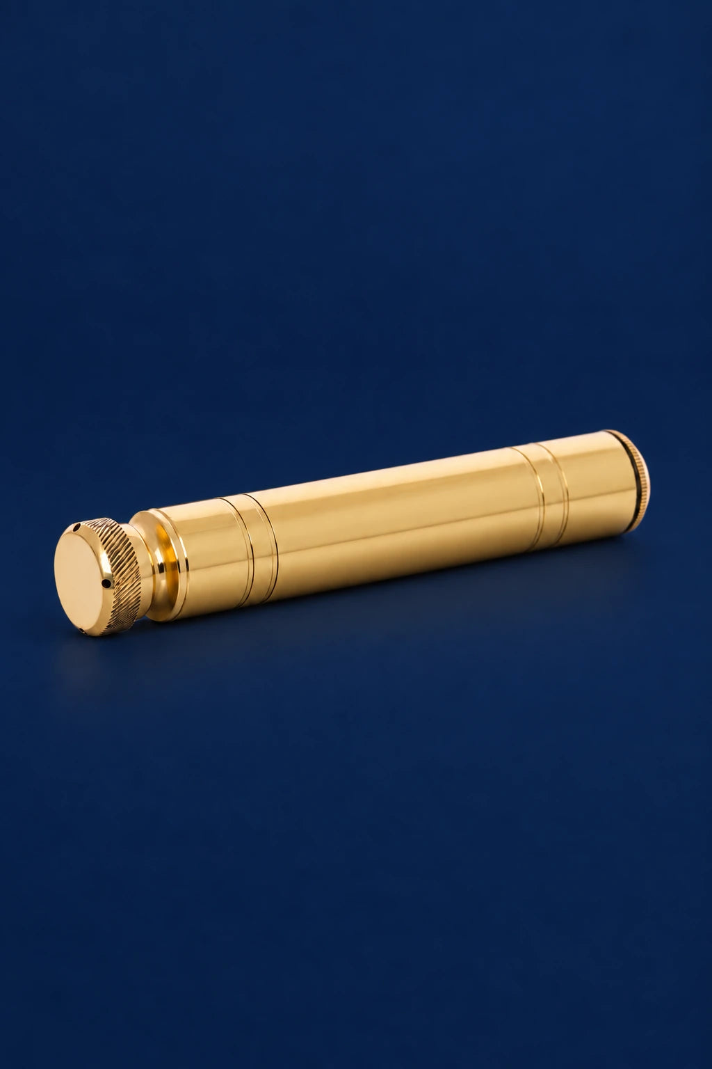 Aspergillum in brass, shown horizontally from the side with ridged end cap and decorative bands