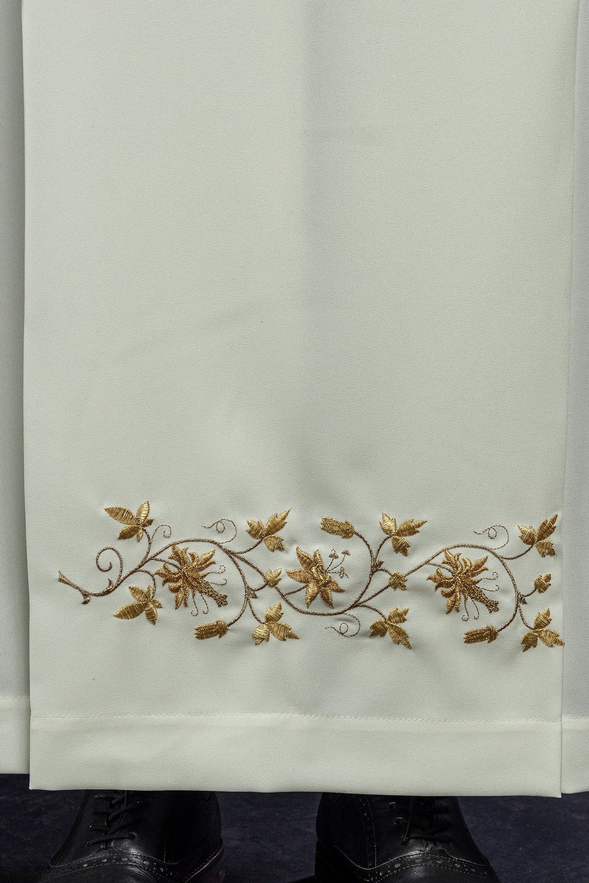 Ecru alb close-up showing gold floral embroidery along the hem