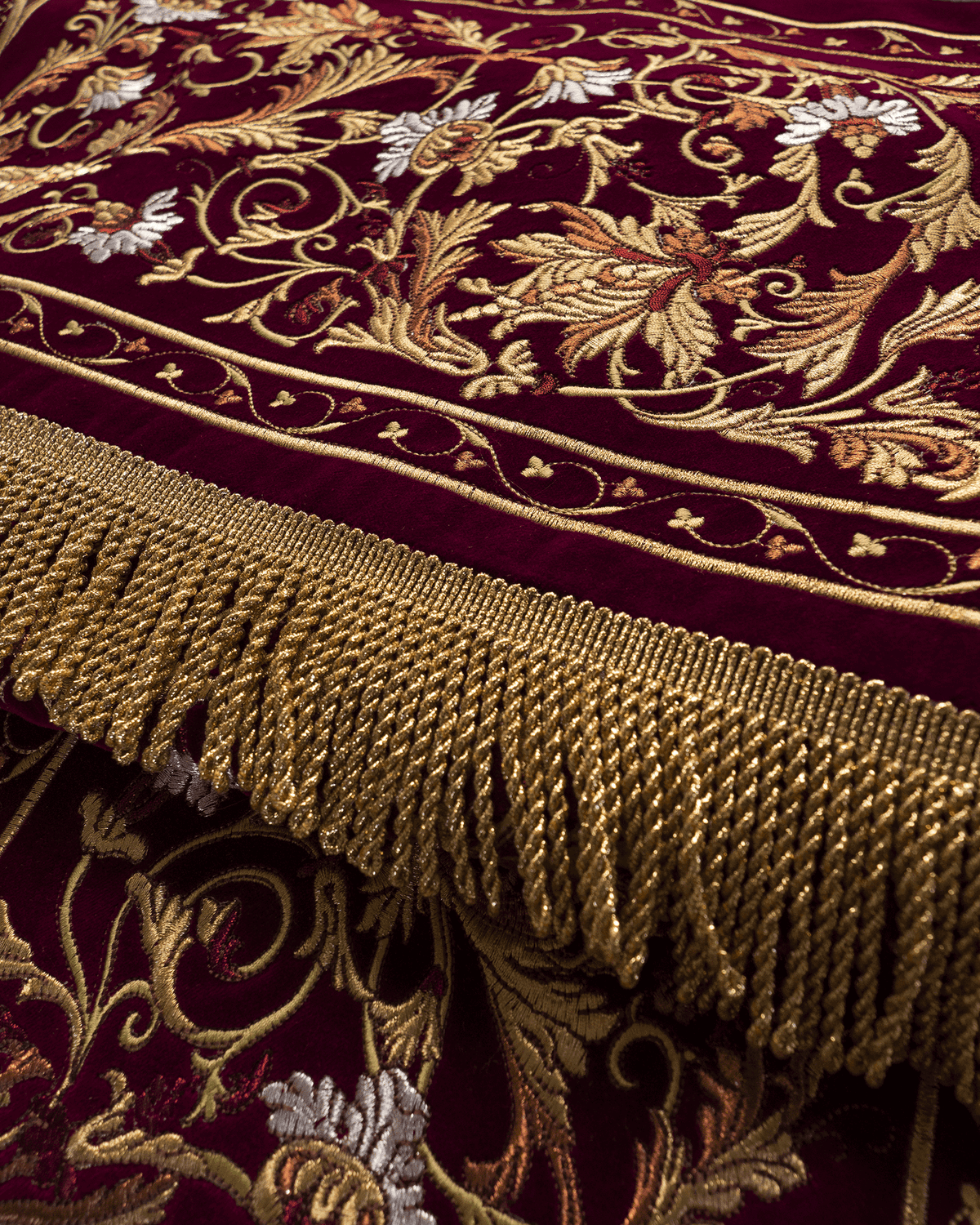 Church canopy close-up showing burgundy embroidered floral motifs and gold fringe