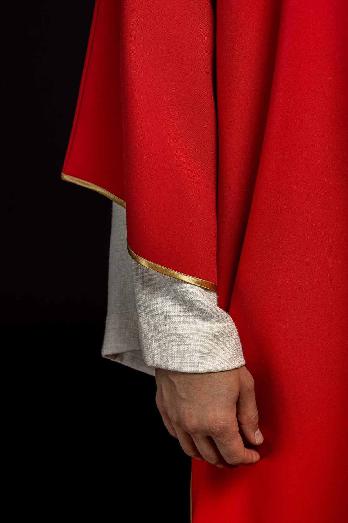 Red dalmatic side close-up showing smooth red fabric and gold sleeve trim