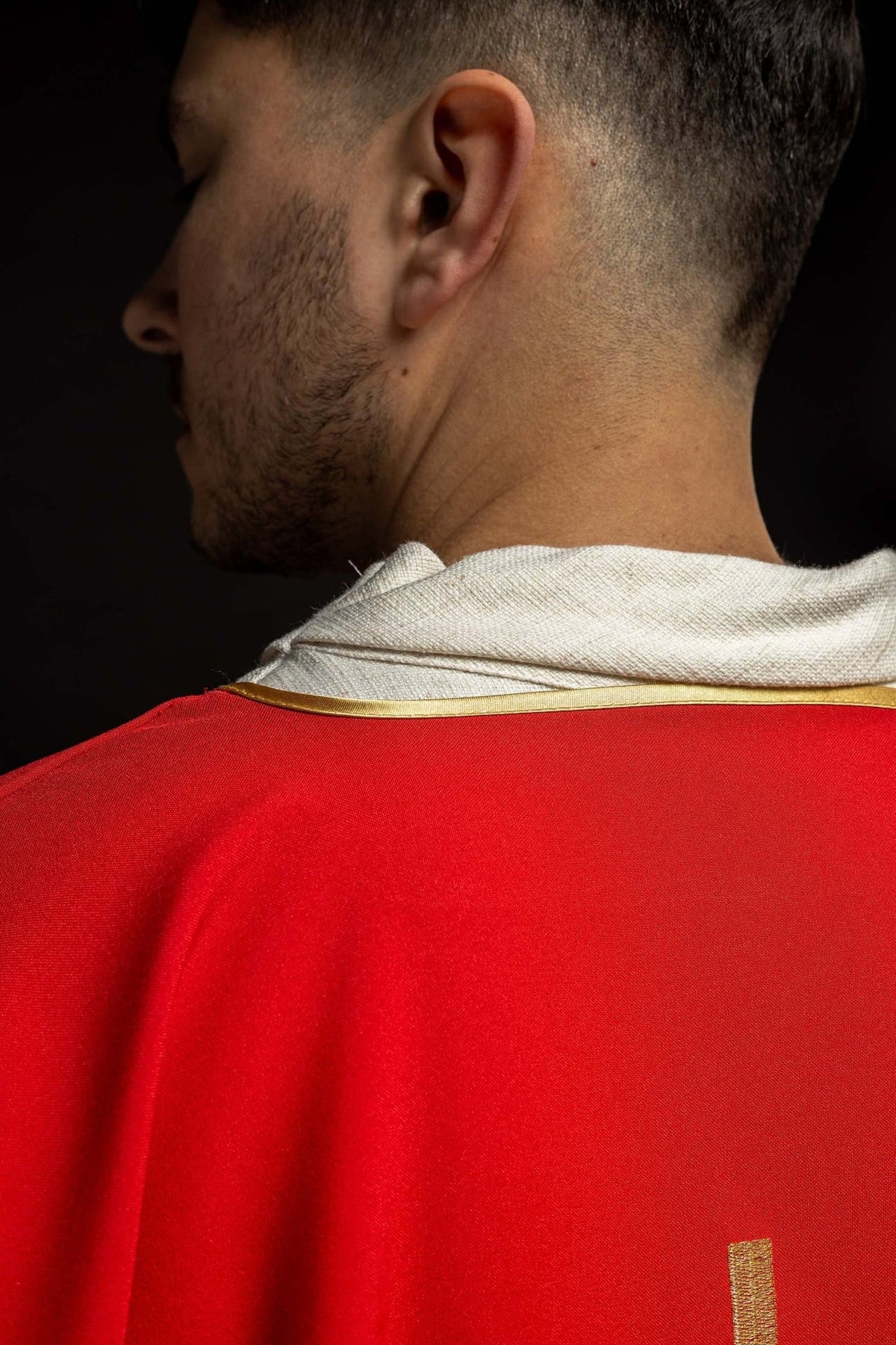Red dalmatic back close-up showing gold-trimmed neckline and red fabric