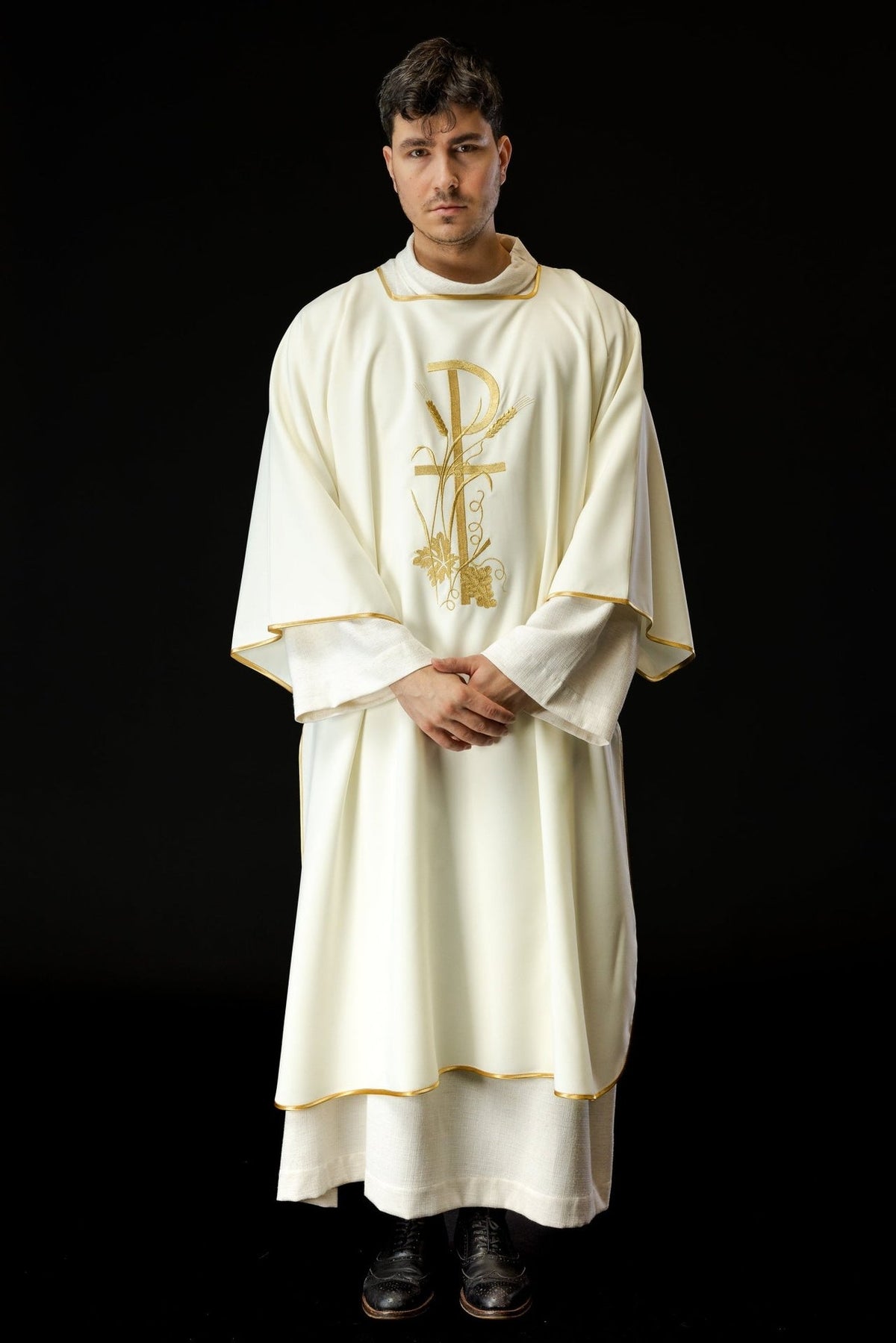 Ecru dalmatic worn from the front, showing gold trim and central floral cross embroidery