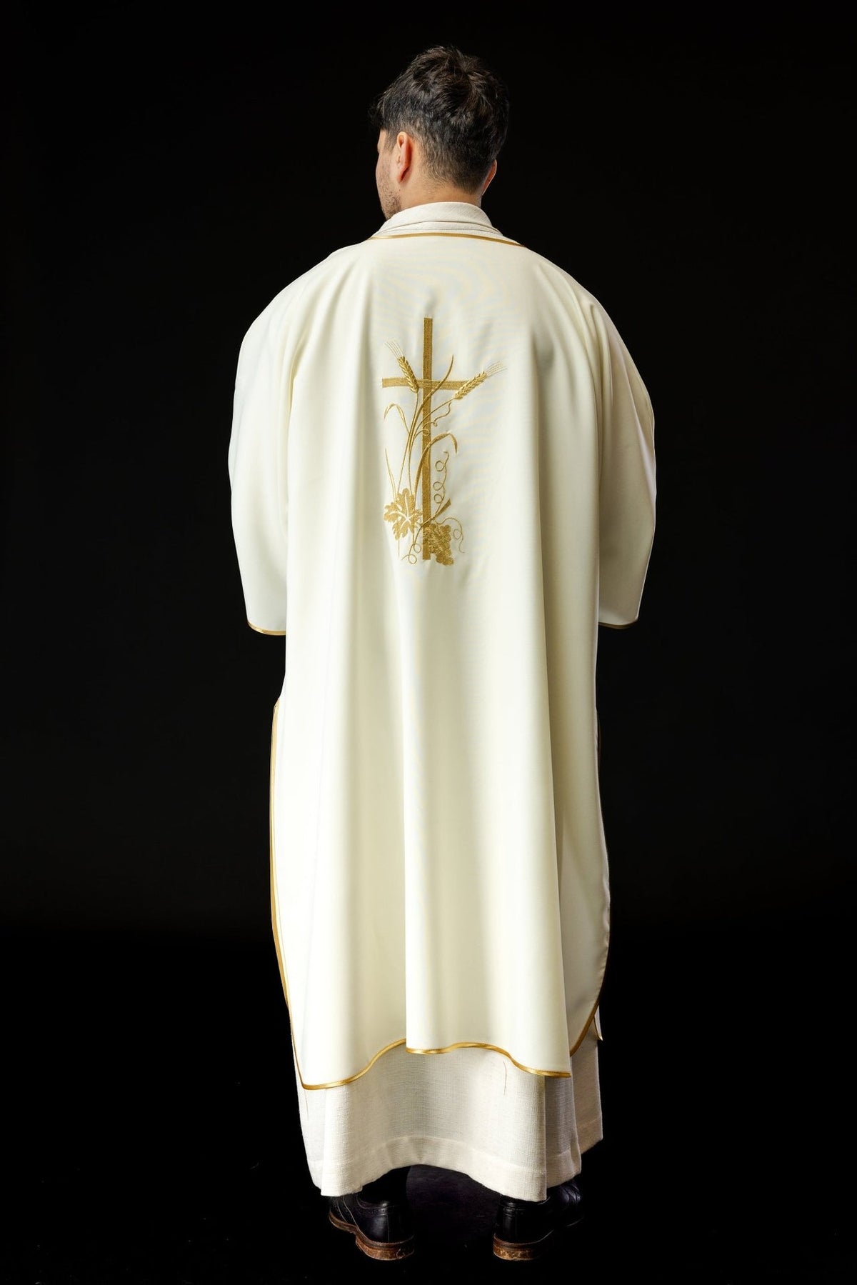 Ecru dalmatic viewed from the back with gold trim and central cross embroidery