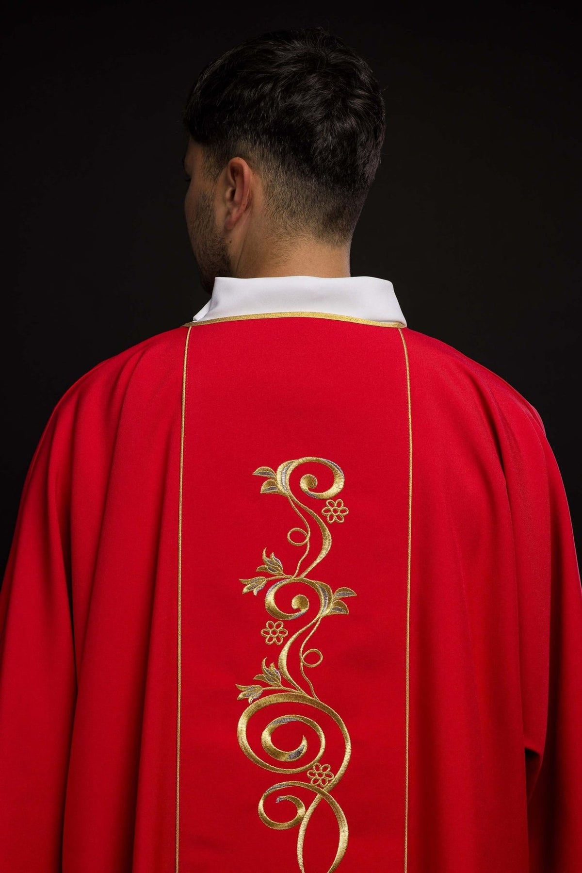 Red dalmatic collar detail with gold trim and embroidered IHS