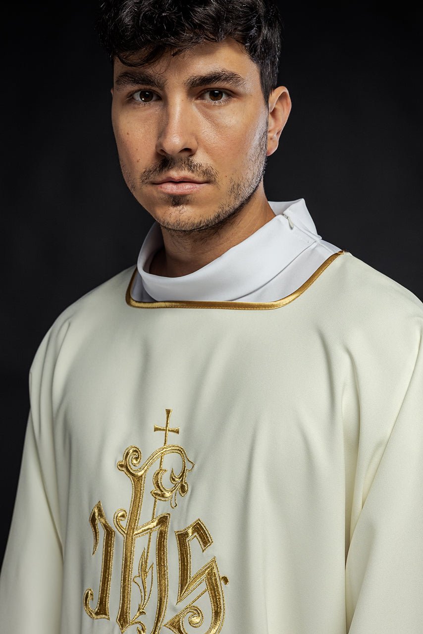 Ecru dalmatic close-up showing gold IHS embroidery and neckline trim