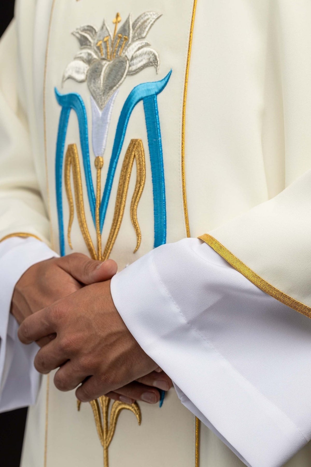 Ecru dalmatic detail showing blue Marian symbol, gold embroidery and gold trim